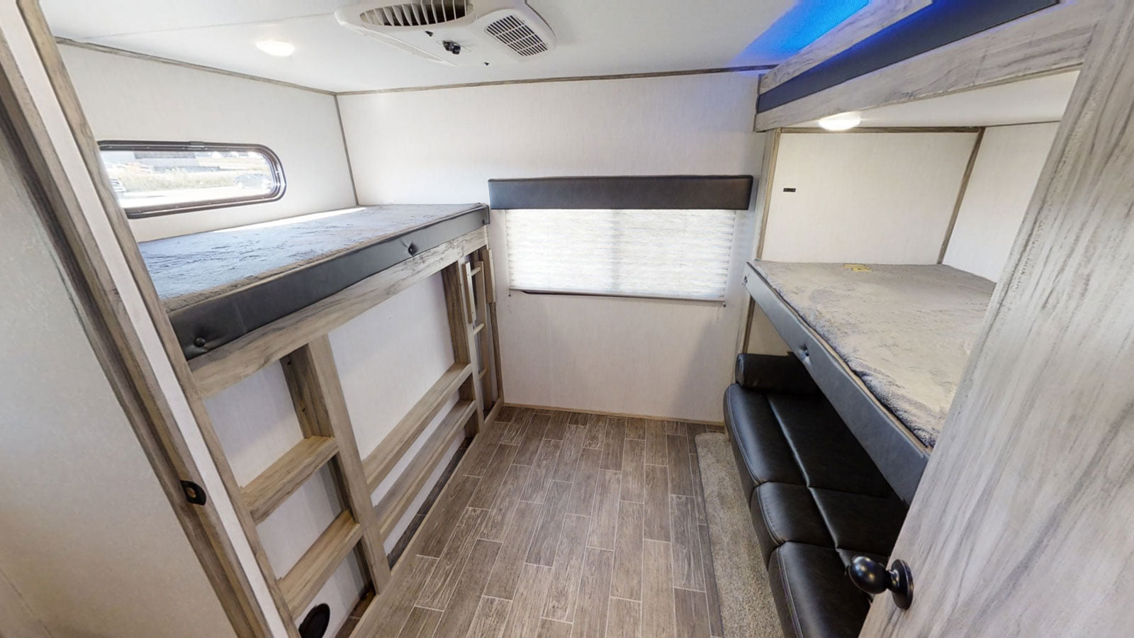 Spacious RV rental bunk room with multiple beds, a window, and comfortable seating, ideal for family travel.. Forest River Cherokee Alpha Wolf 2020