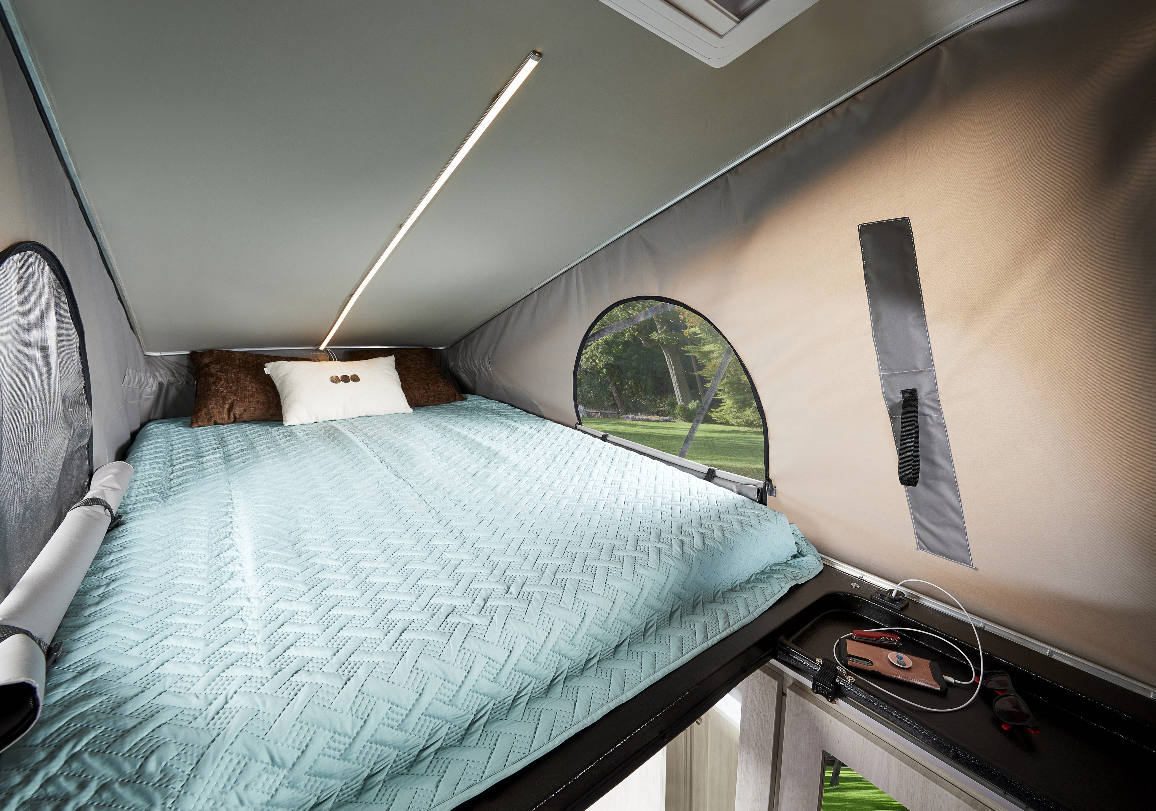 Cozy RV rental pop-top camper interior: a comfy bed with LED light, window view, and convenient charging station by the bed.. Dodge Ram ProMaster RoadTrek Zion Slumber 2023
