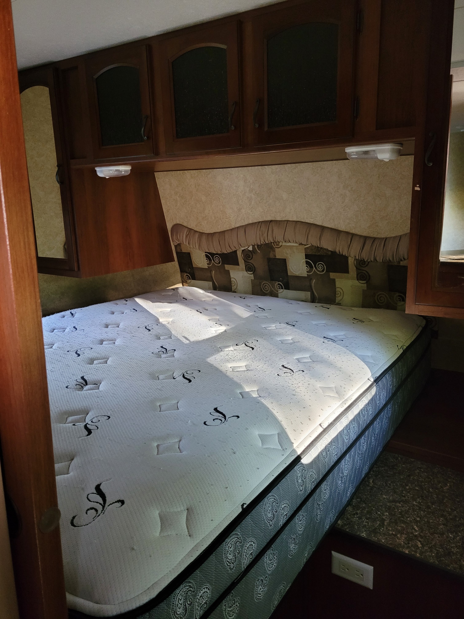 Comfortable RV rental bedroom with a neatly made bed and overhead cabinets, ready for your next adventure.. Forest River Lacrosse 2011