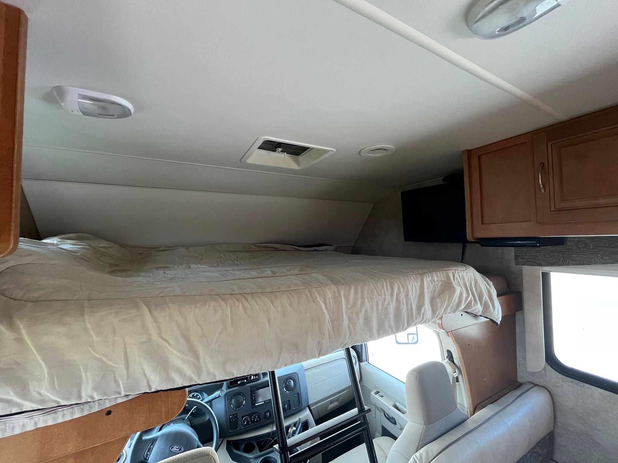 Spacious RV rental interior featuring a large cab-over bunk bed, driver's cabin, and overhead lights. Ready for adventure!. Winnebago Minnie Winnie 2014