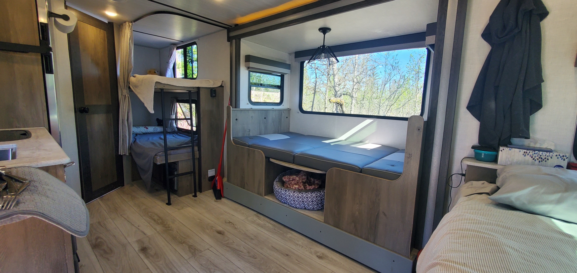 Bright RV rental interior with bunk beds, convertible dinette, kitchen, and pet bed. Cozy camping!. Forest River Surveyor Legend 2022
