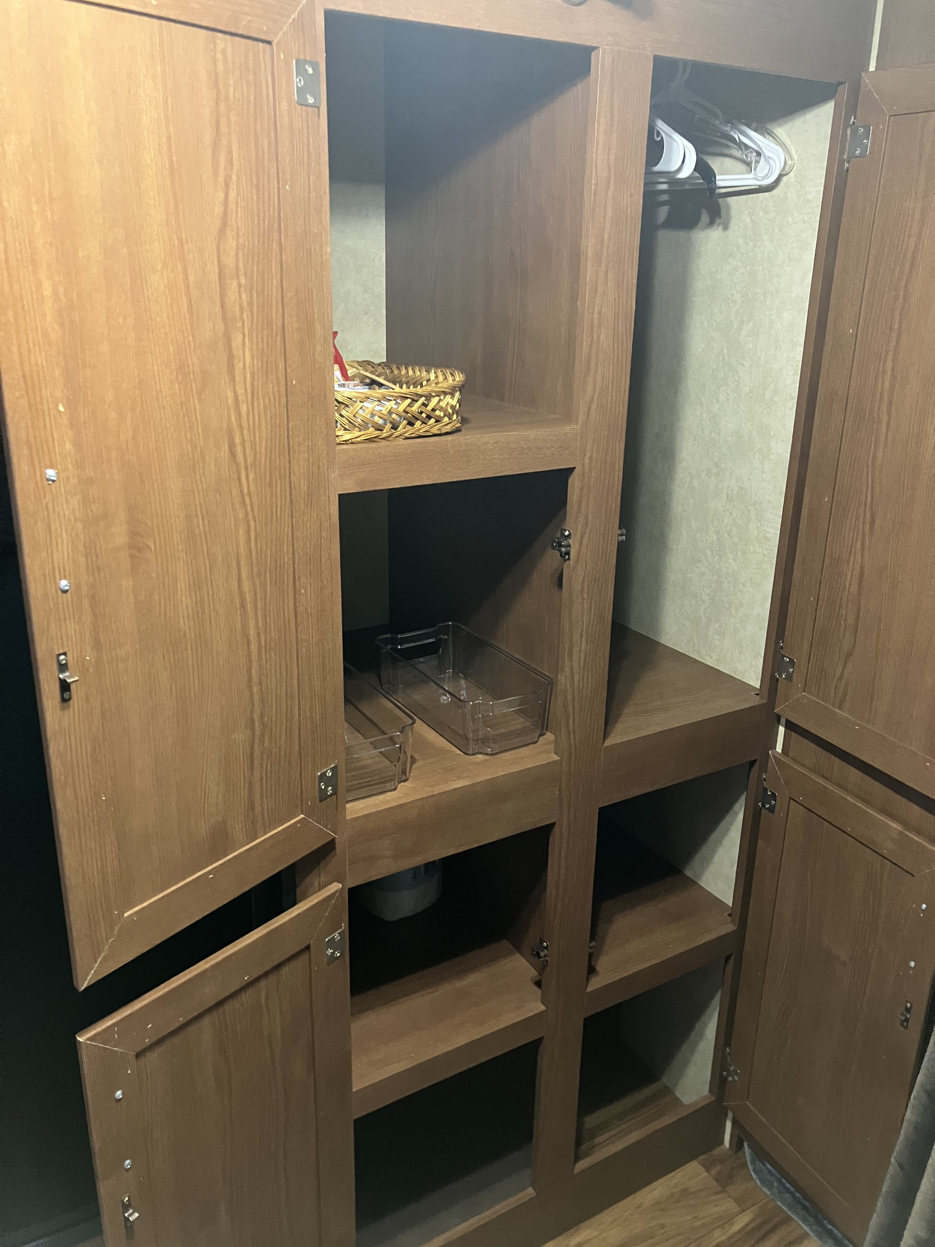 Open RV rental wardrobe features multiple shelves, a hanging rod with hangers, and clear storage bins for organized packing.. Forest River Wildwood X-Lite 2016