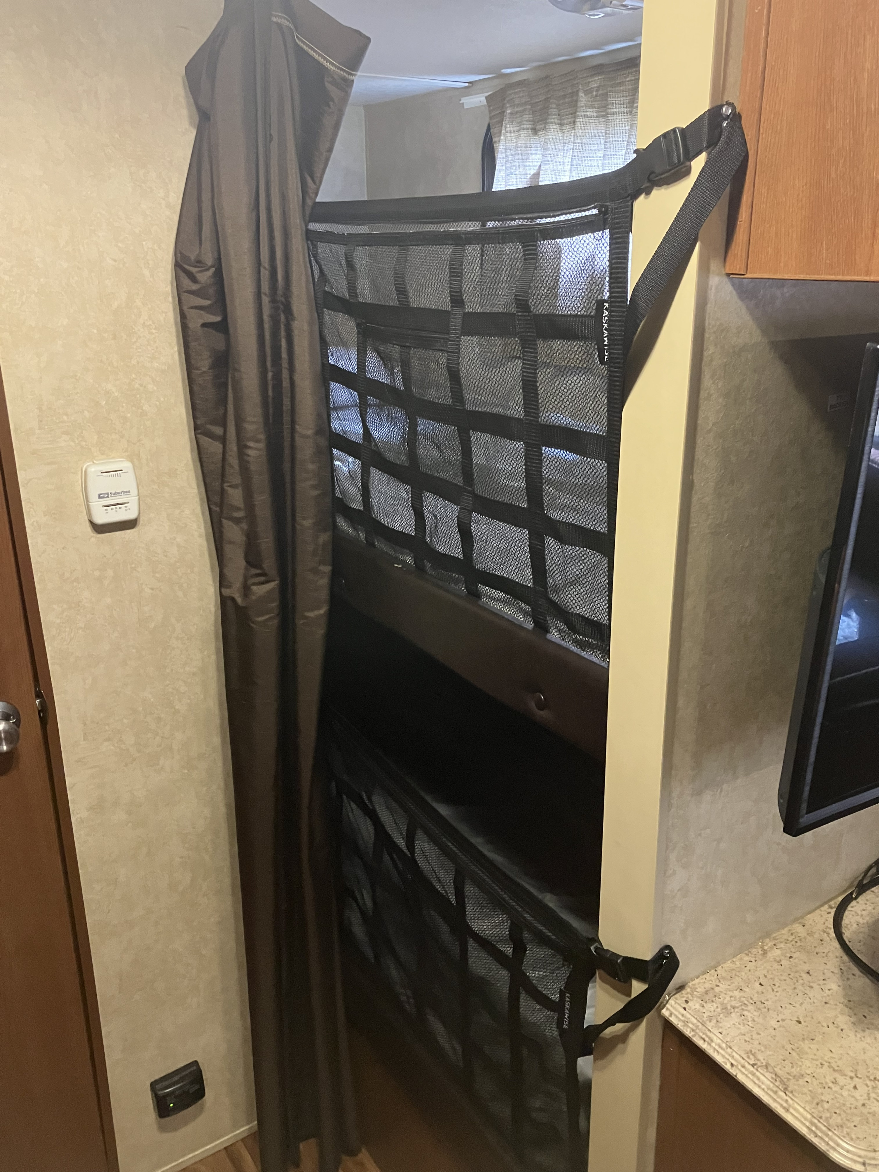RV rental: Bunk beds with a black safety net and a brown privacy curtain. A thermostat is on the wall.. Forest River Wildwood X-Lite 2016