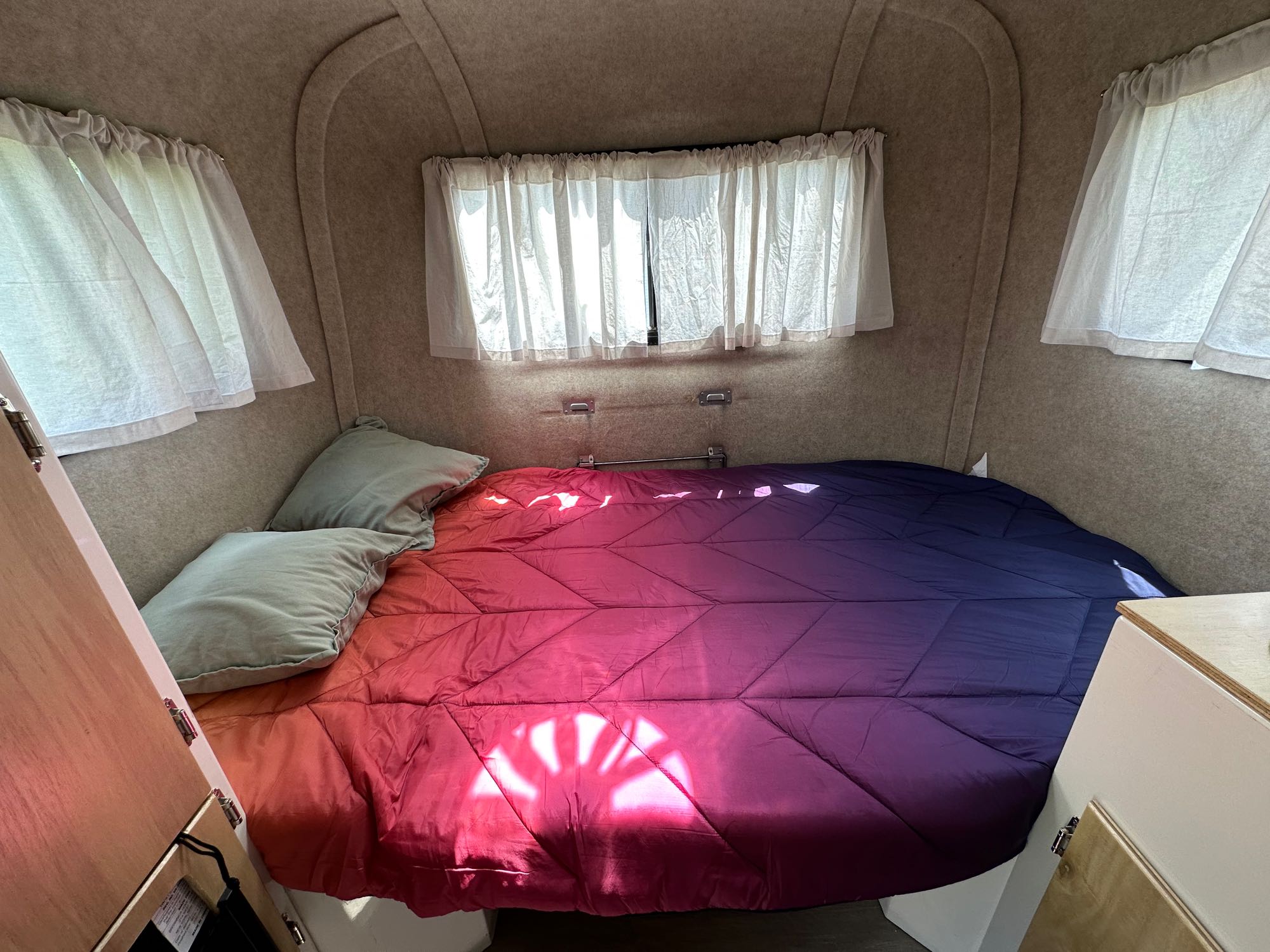 Experience comfort in this RV rental! A cozy camper bedroom features an ombre comforter & pillows, bathed in sunlight from side windows.. Scamp Scamp Trailer 2010
