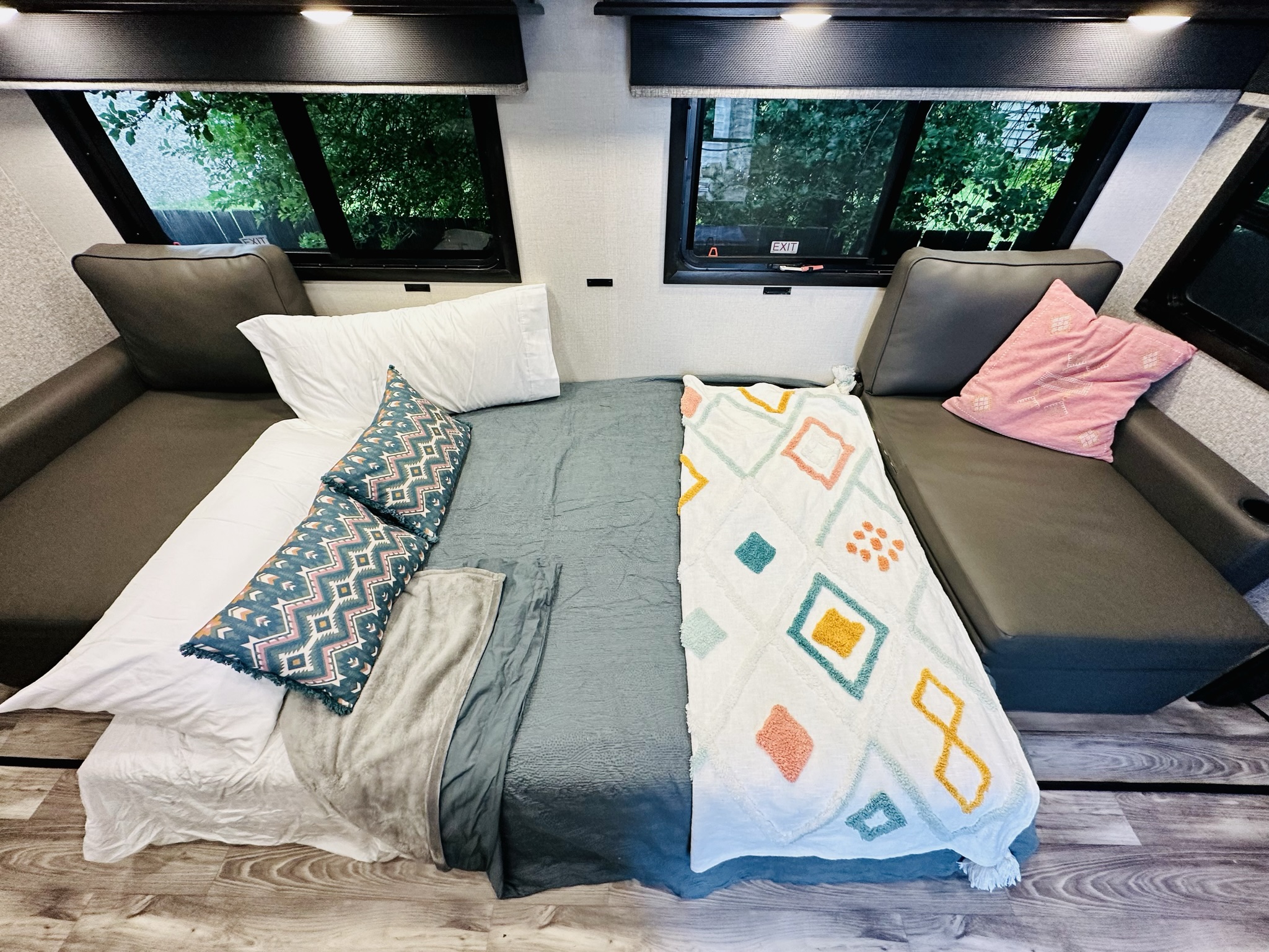 Cozy RV rental interior featuring a neatly made bed with colorful blankets between two dark couches, perfect for a comfortable travel stay.. Highland Ridge RV Mesa Ridge 2022