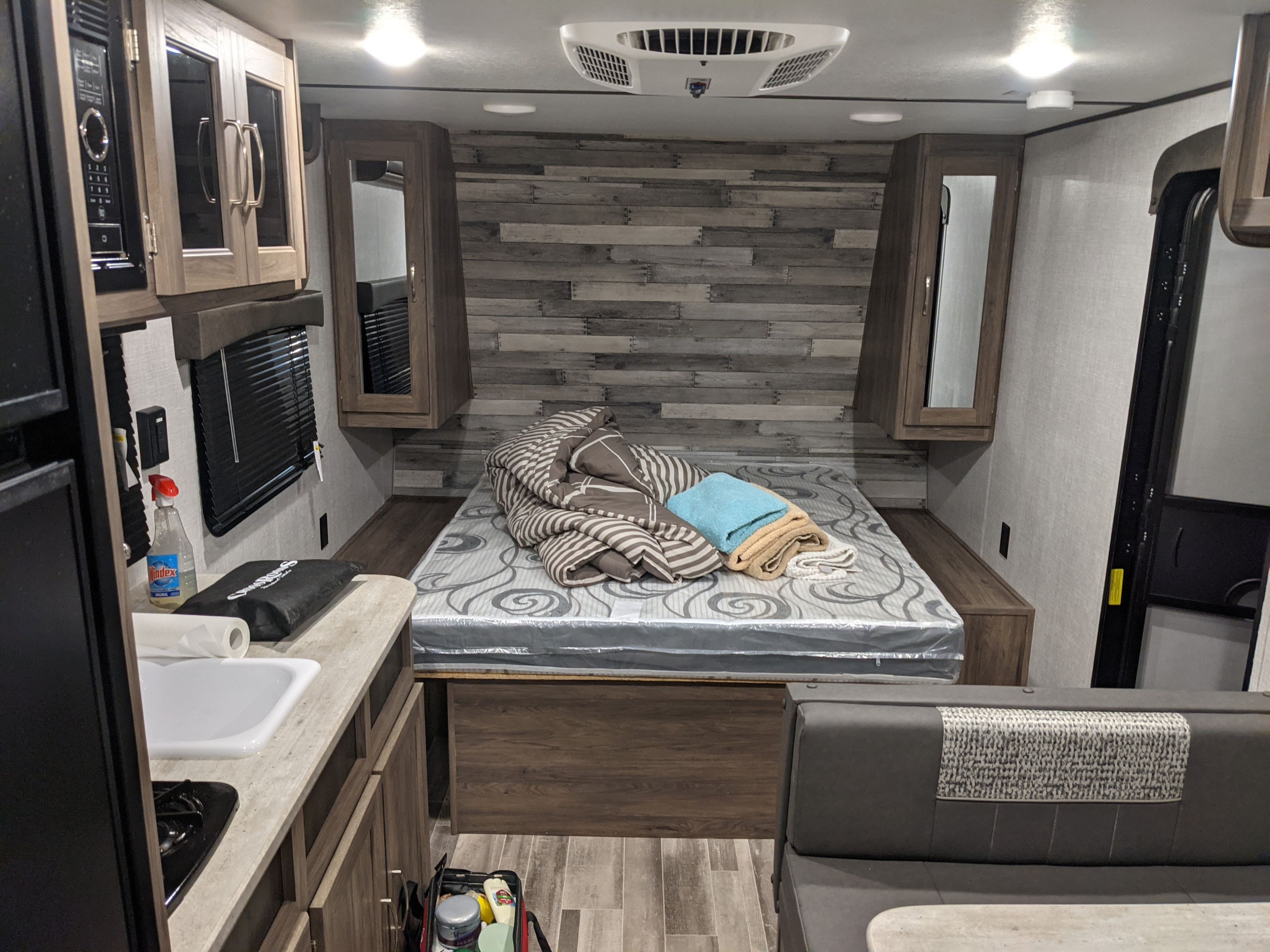 Inside a modern RV rental: a compact living space with a cozy bed, functional kitchenette, and dinette.. Crossroads RV Zinger Lite 2021