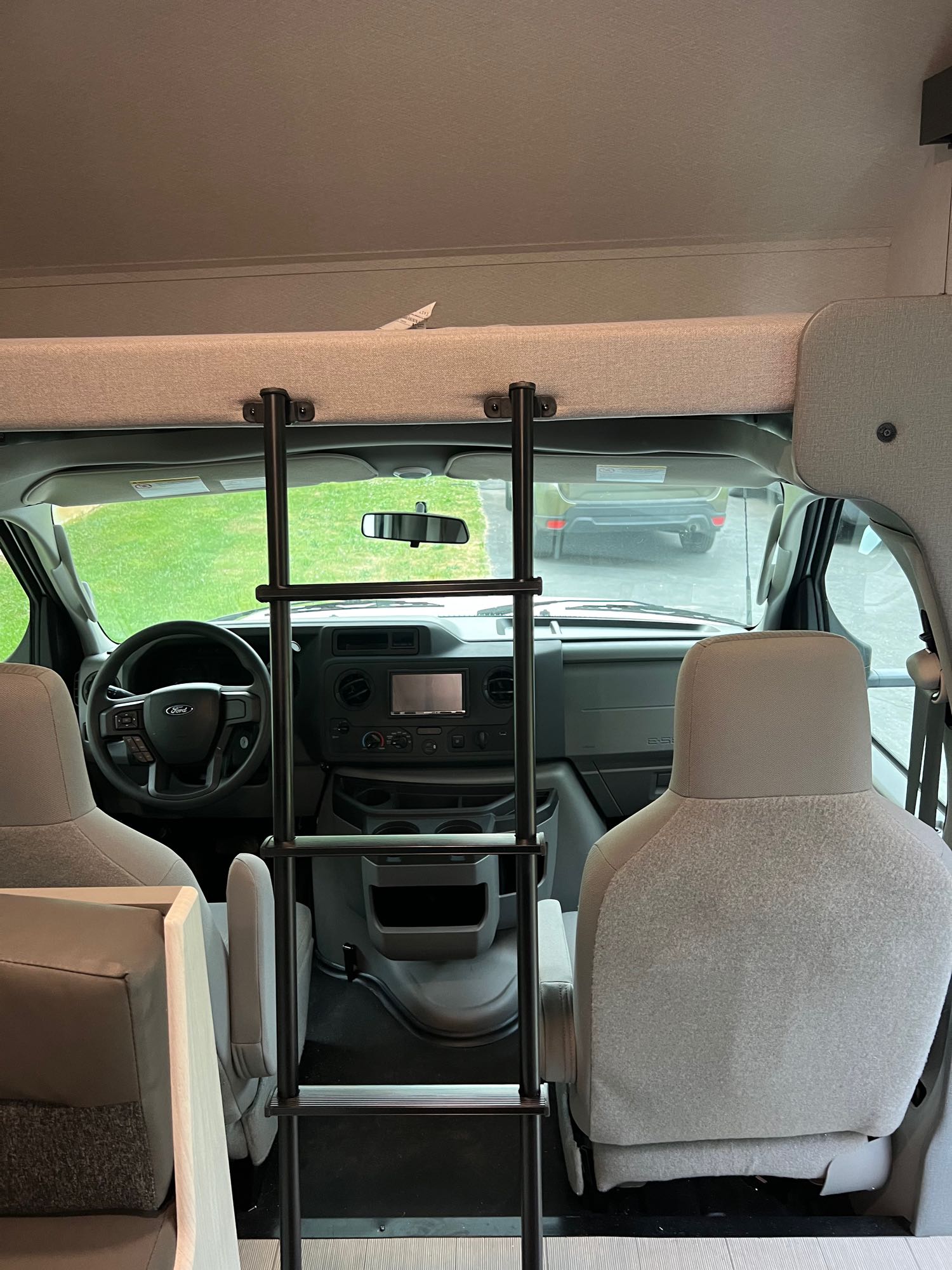 RV rental interior: Front cabin with overhead bunk and ladder, showing driving area and passenger seats.. EAST TO WEST ENTRADA 2600DS 2023