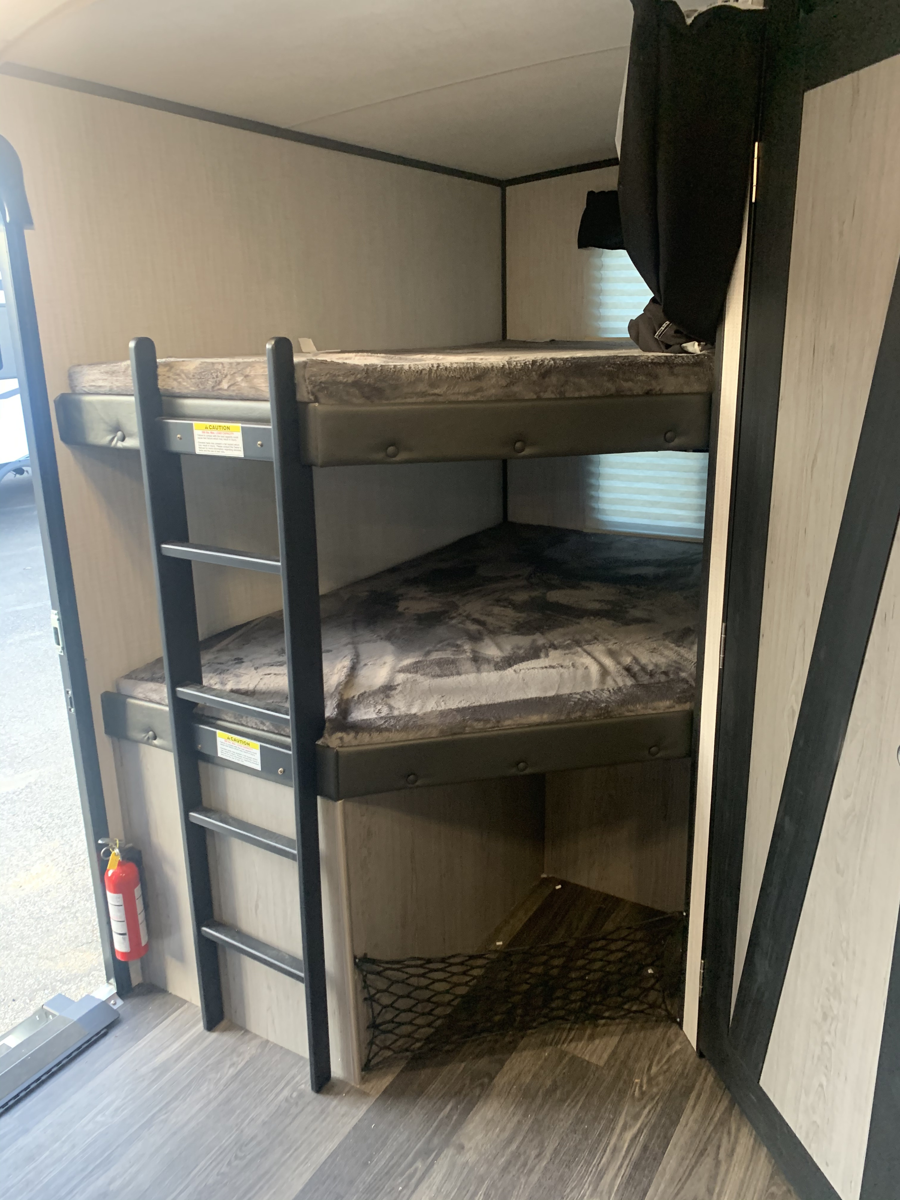 RV rental interior featuring bunk beds with a ladder, bottom storage net, and a fire extinguisher for safety.. Heartland RVs Mallard 2021