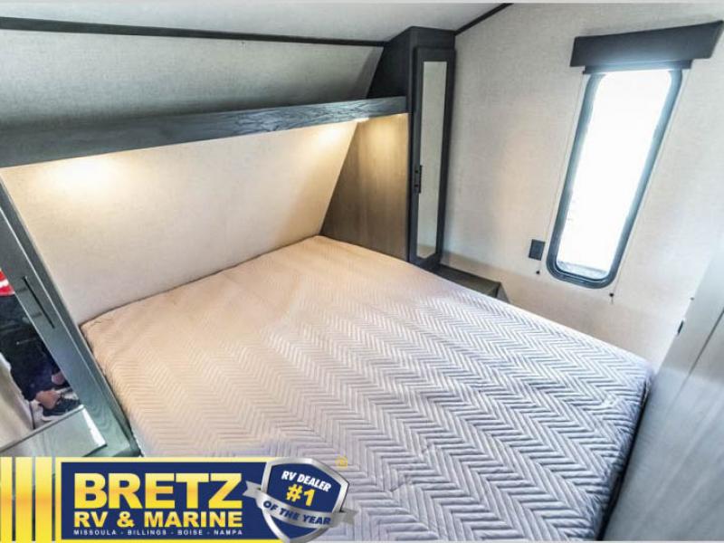 An RV bedroom features a comfy bed with chevron quilt, lighted headboard, and window. Great for your rv rental.. Dutchmen Aspen Trail 2340BHSWE 2022