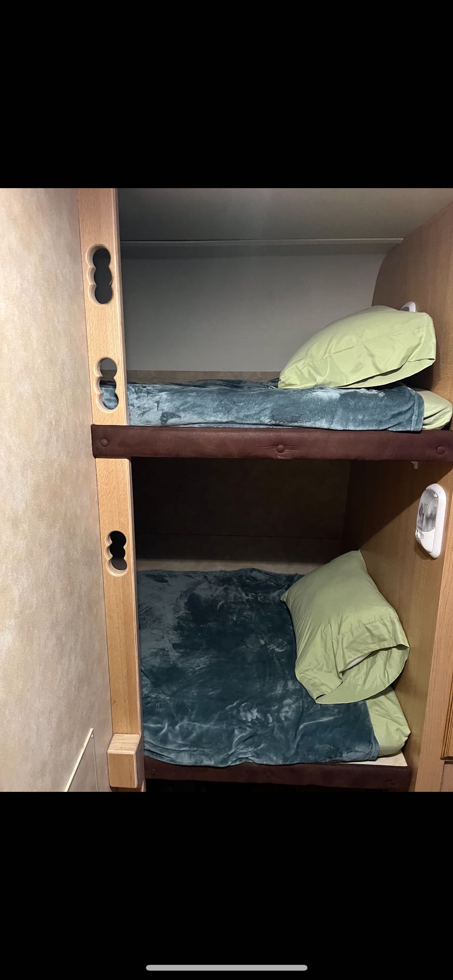 Cozy RV rental bunk beds, ready for rest. Features green pillows, blue blankets, ideal for compact travel.. K-Z Manufacturing Spree 2010