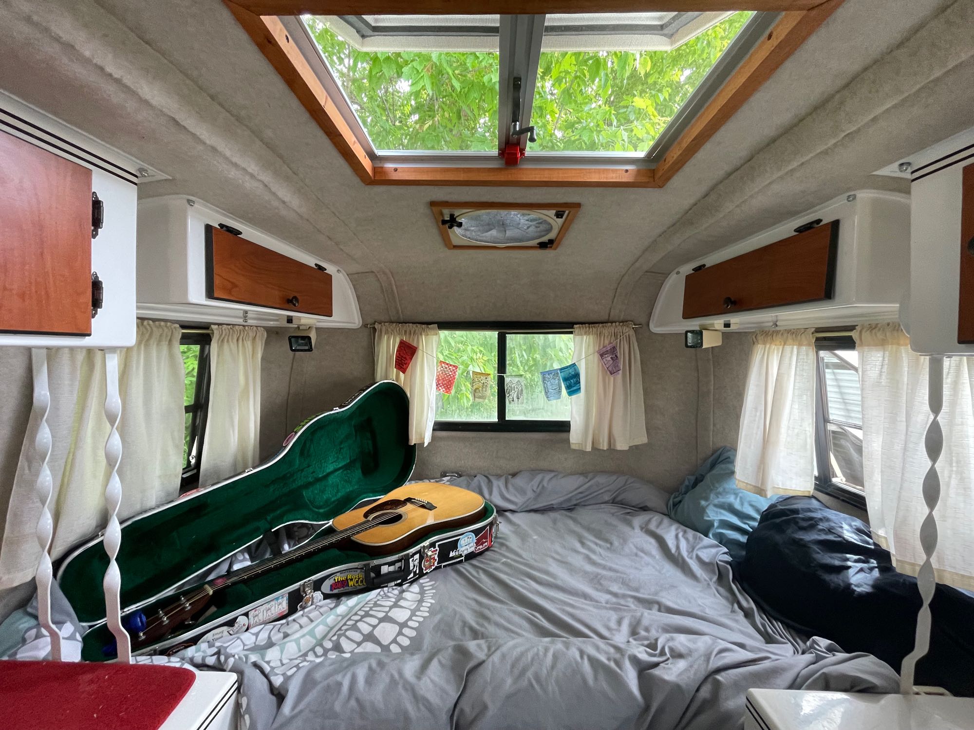 Cozy RV rental interior with a guitar on the bed, offering comfort for travel adventures.. Scamp Scamp Trailer 2014
