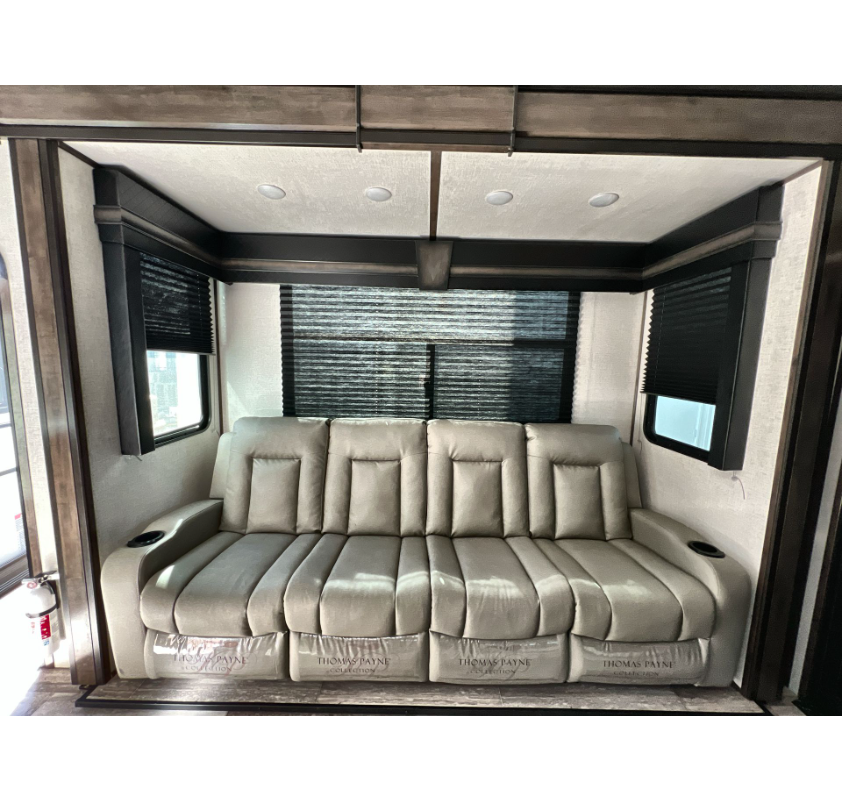 RV rental's cozy interior: a light gray Thomas Payne reclining sofa with cupholders, large windows, and blackout blinds.. Dutchmen Voltage 2022