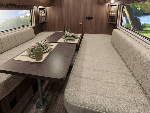 Spacious RV rental interior with a comfortable dinette, cozy bench seating, two tables, and large windows for scenic views.. Winnebago Trend 2016