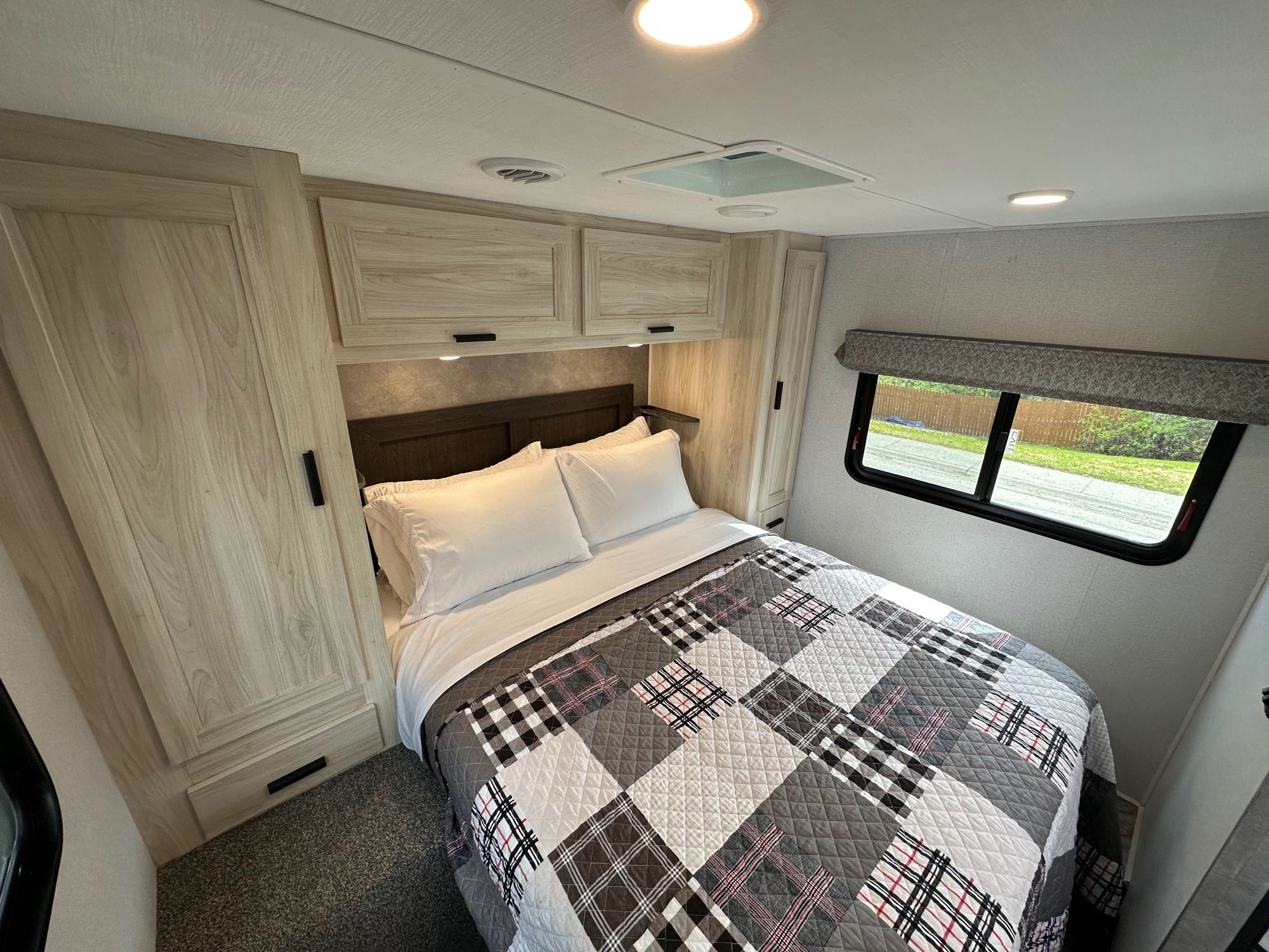 Inviting RV rental bedroom with a neatly made bed, light wood cabinets, & bright lighting. A comfortable, compact space.. Forester LE 2022