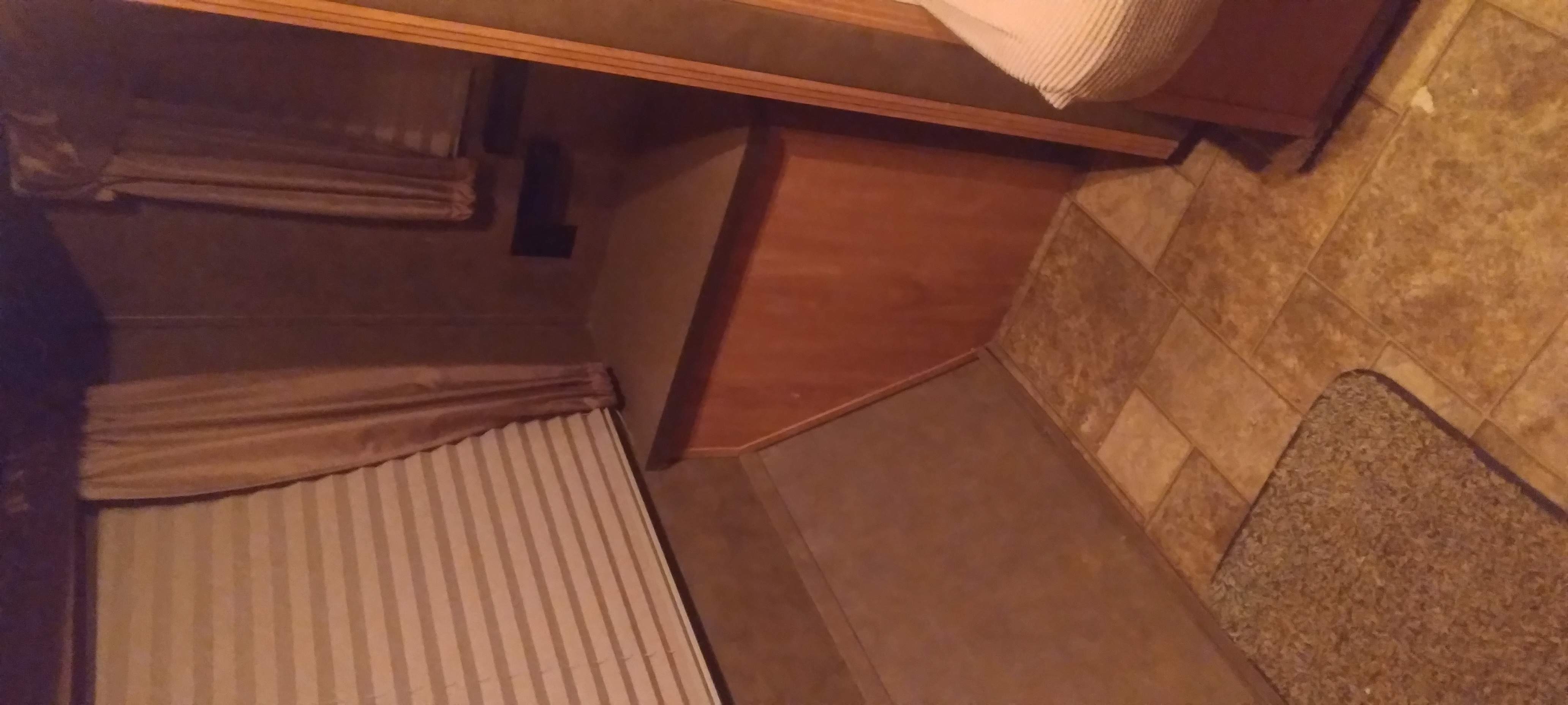 RV rental interior features cozy striped bed, wood cabinetry, and tile/carpet flooring, ideal for travel.. Forest River Shasta Flyte 2015