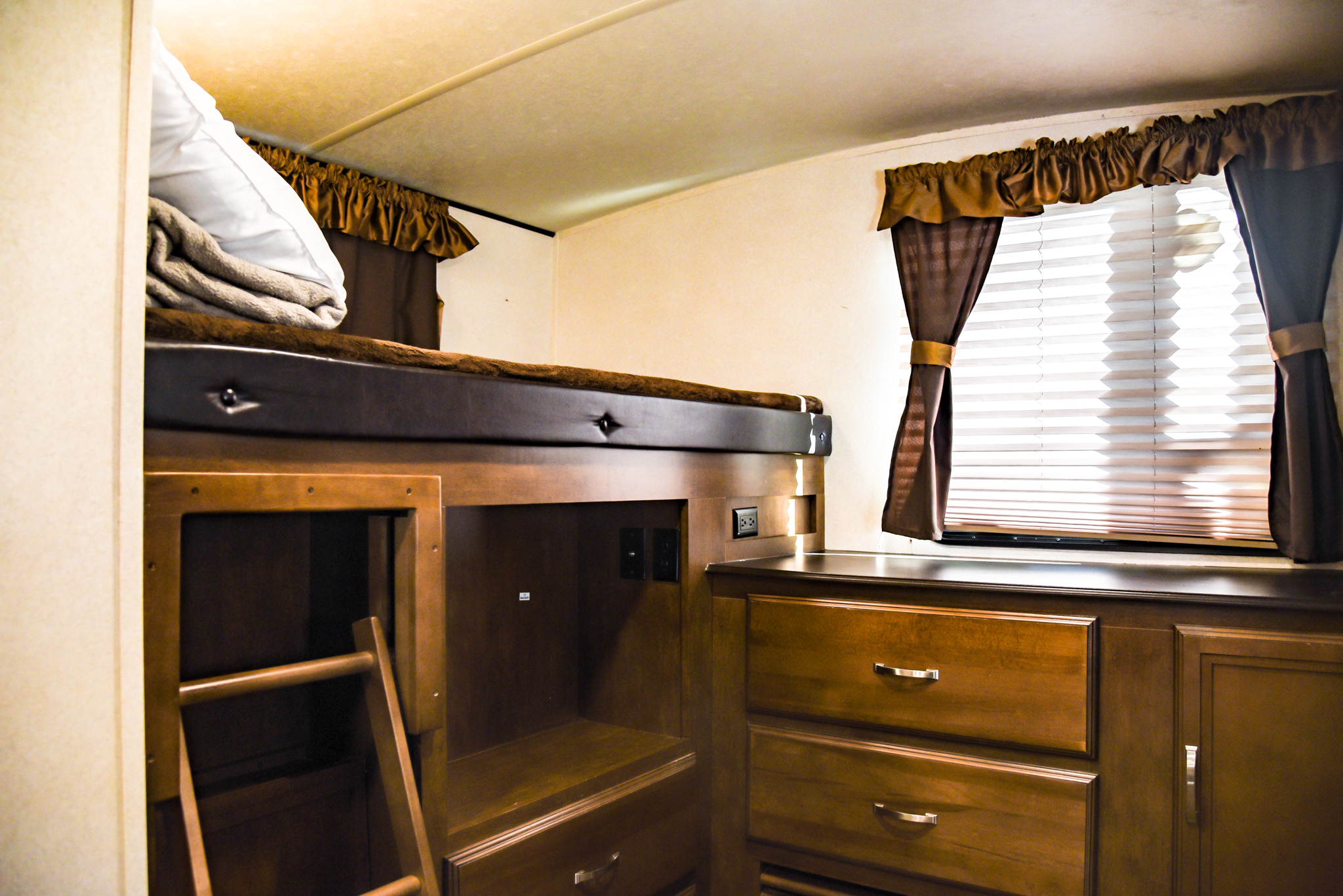 RV rental interior with cozy bunk beds, a ladder, storage, and a window with blinds and curtains.. Forest River Wildwood Heritage Glen Lite 2018