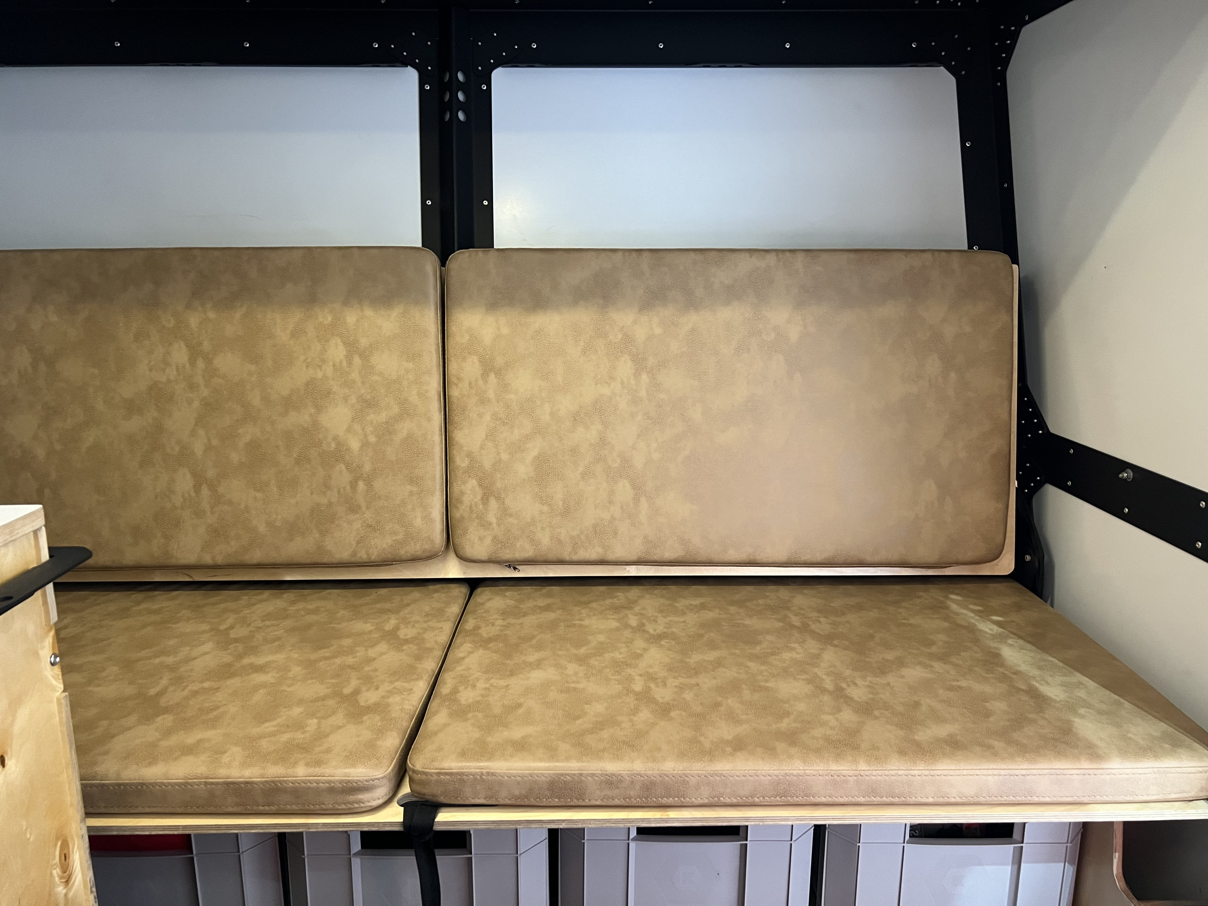 Inside an RV rental: a cozy seating area with tan cushions and built-in storage.. TAXA TAXA Trailer 2021
