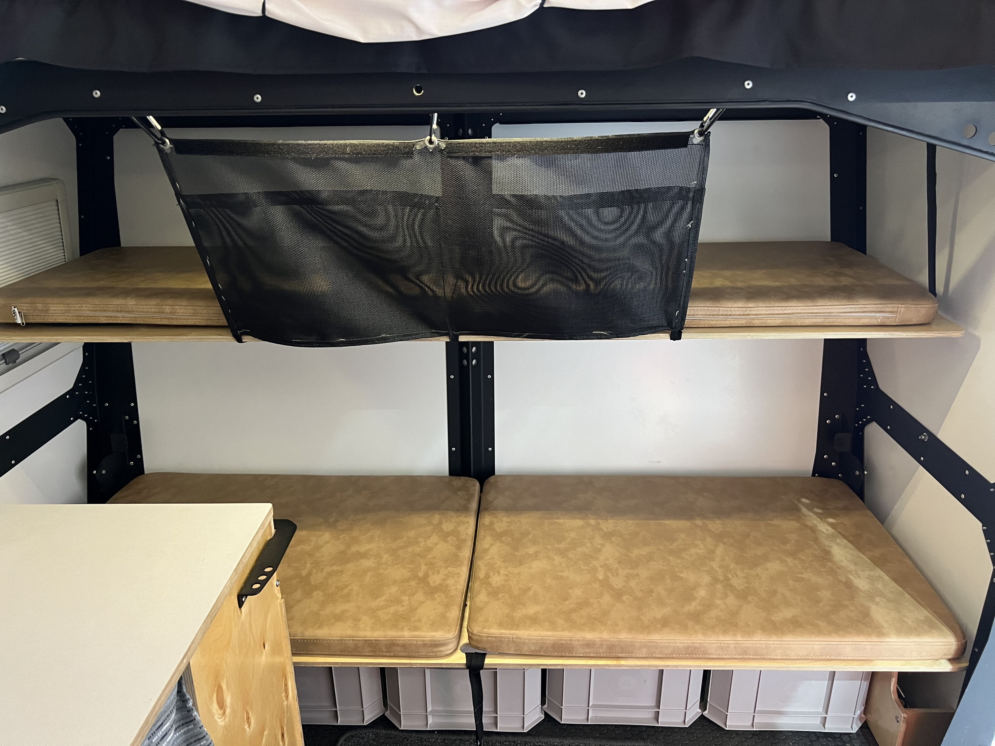 Spacious RV rental interior with bunk beds, under-bed storage bins, and hanging mesh organizer.. TAXA TAXA Trailer 2021