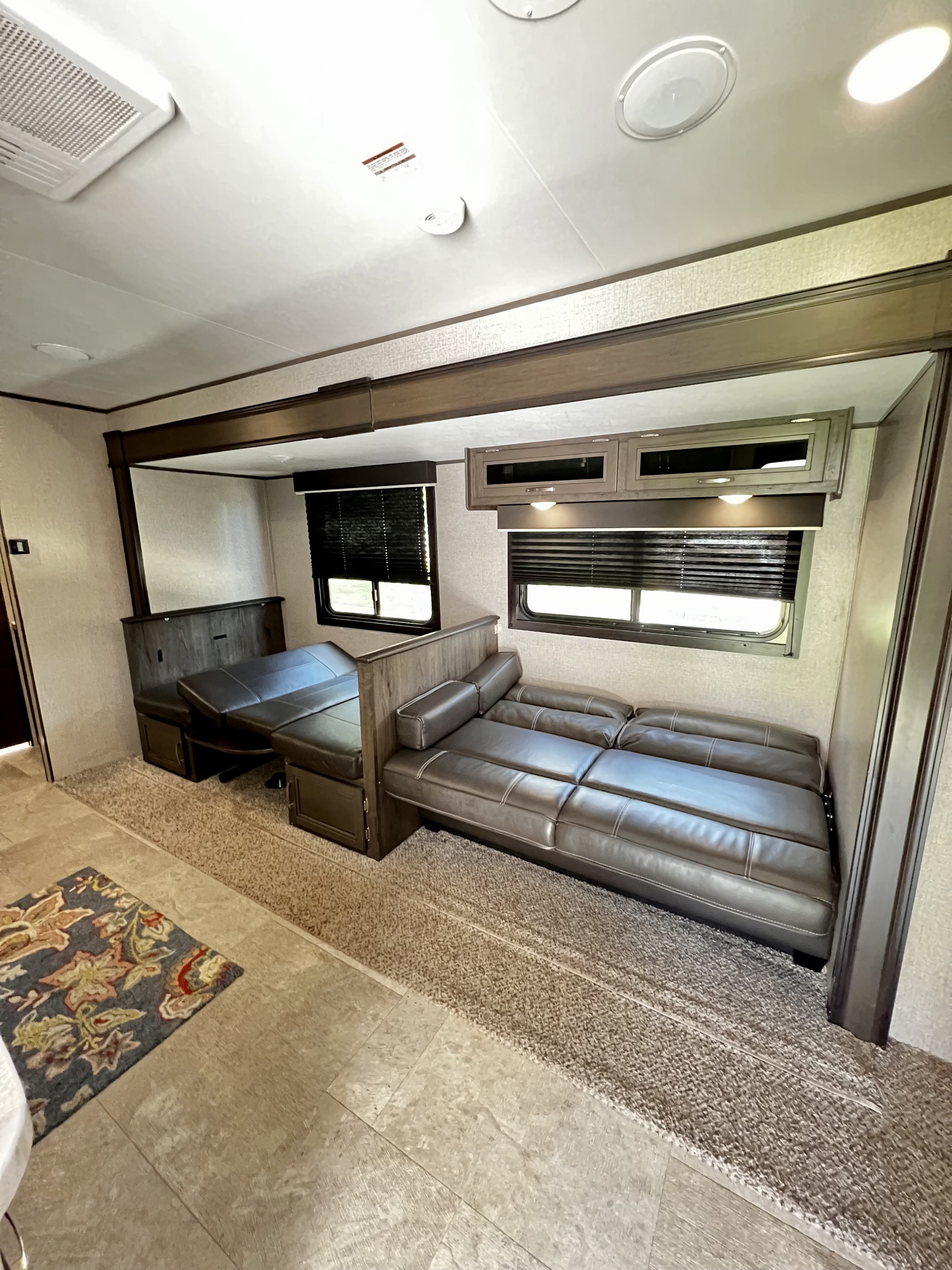 RV rental interior with versatile seating: a dining booth and a long sofa, overhead cabinets, and windows for comfortable travel.. Jayco Jay Flight SLX 2020