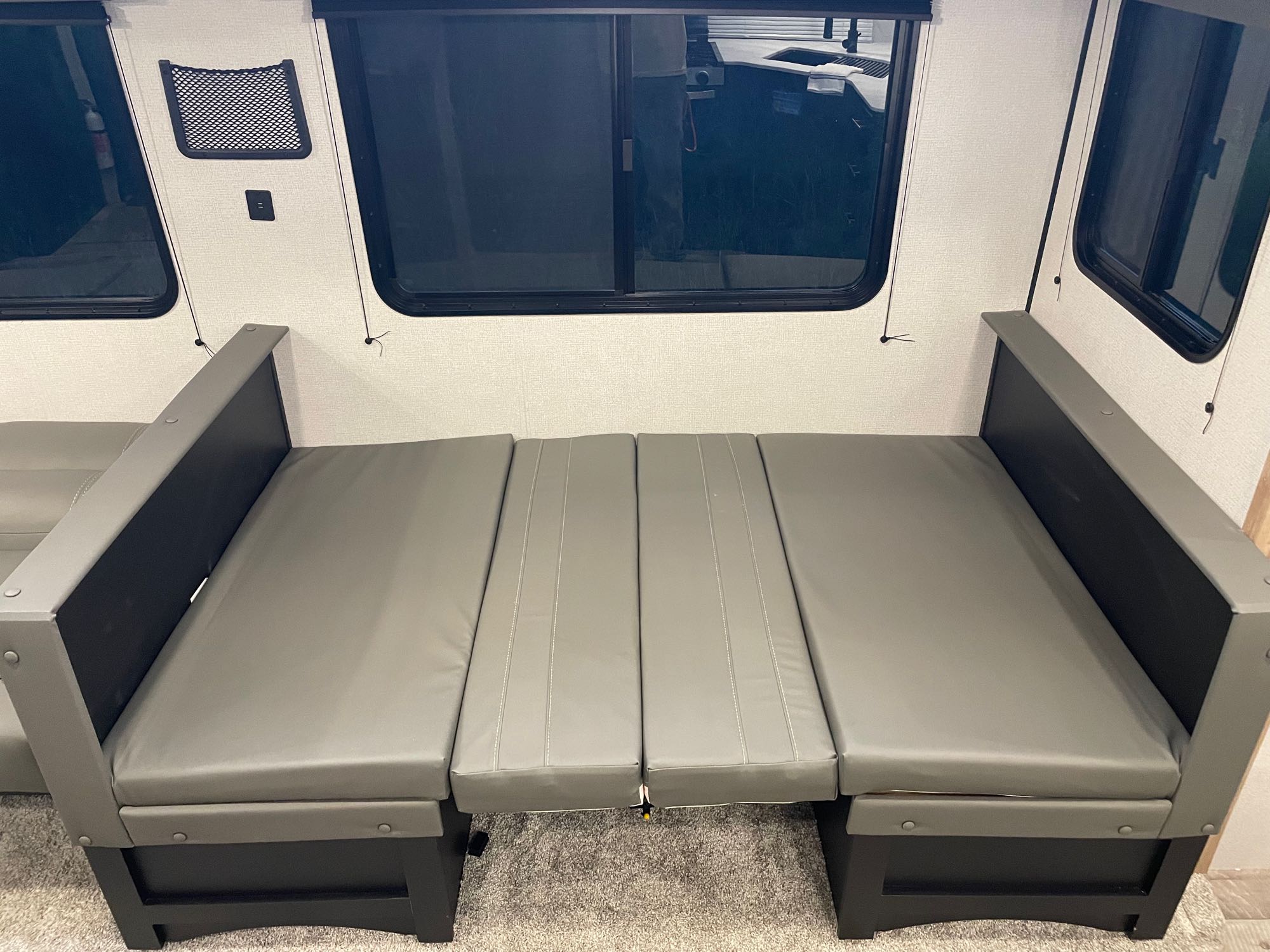 RV rental interior: Grey convertible dinette/bed area with wall-mounted USB port & mesh pocket next to windows.. Keystone RV Springdale 2022