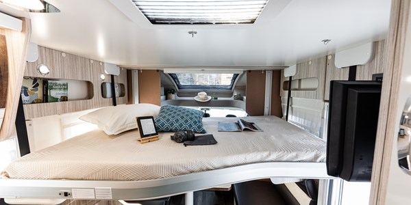 Comfortable RV rental bedroom interior with a bed, e-reader, and TV, offering a cozy space for travel.. Elnagh 582 2023