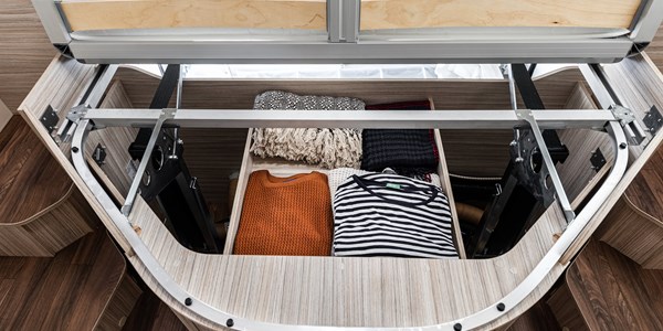 RV rental smart storage: under-bed space neatly holds folded sweaters and blankets in custom compartments.. Elnagh 582 2023