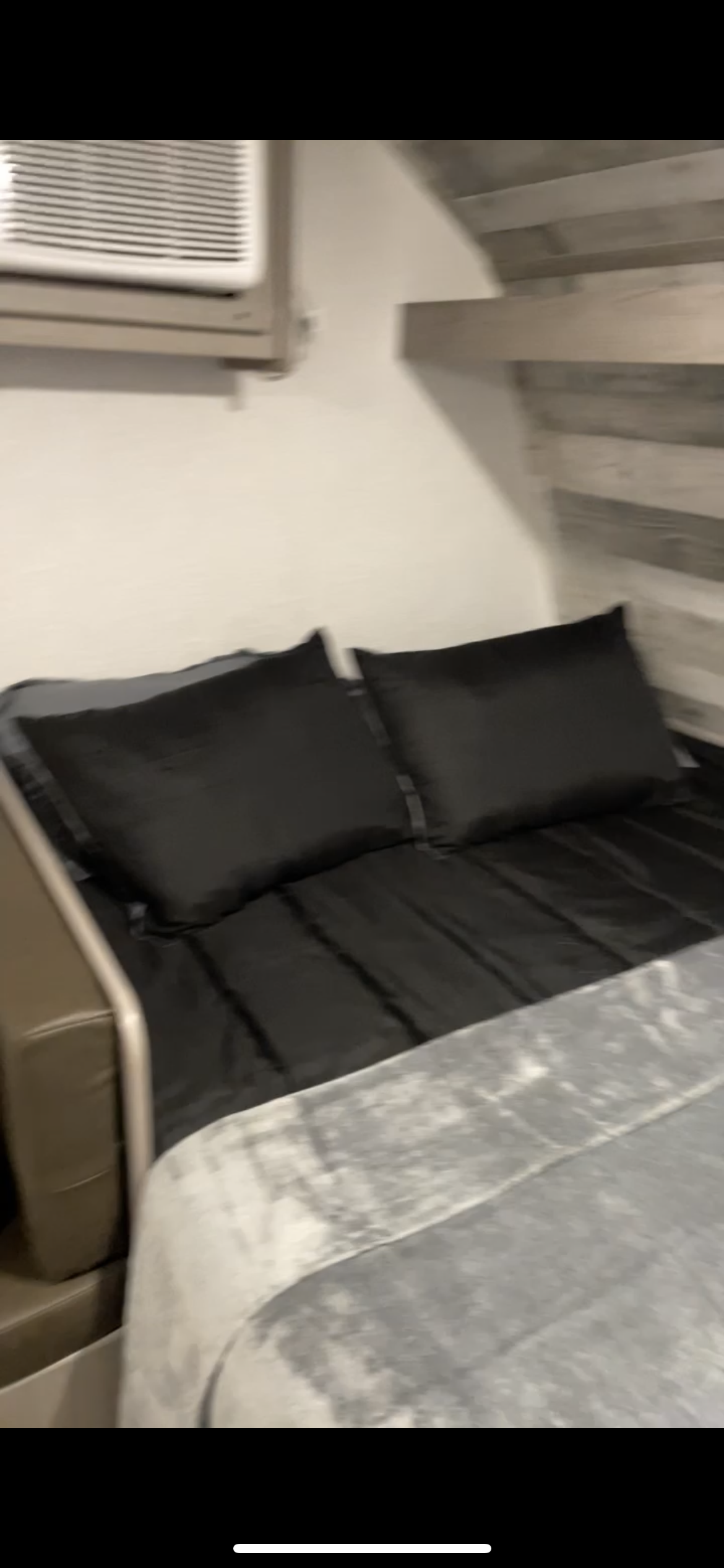 RV rental: Cozy sleeping area with black bedding, pillows, a gray blanket, and an AC unit for comfort.. Coleman Lantern 17B 2023