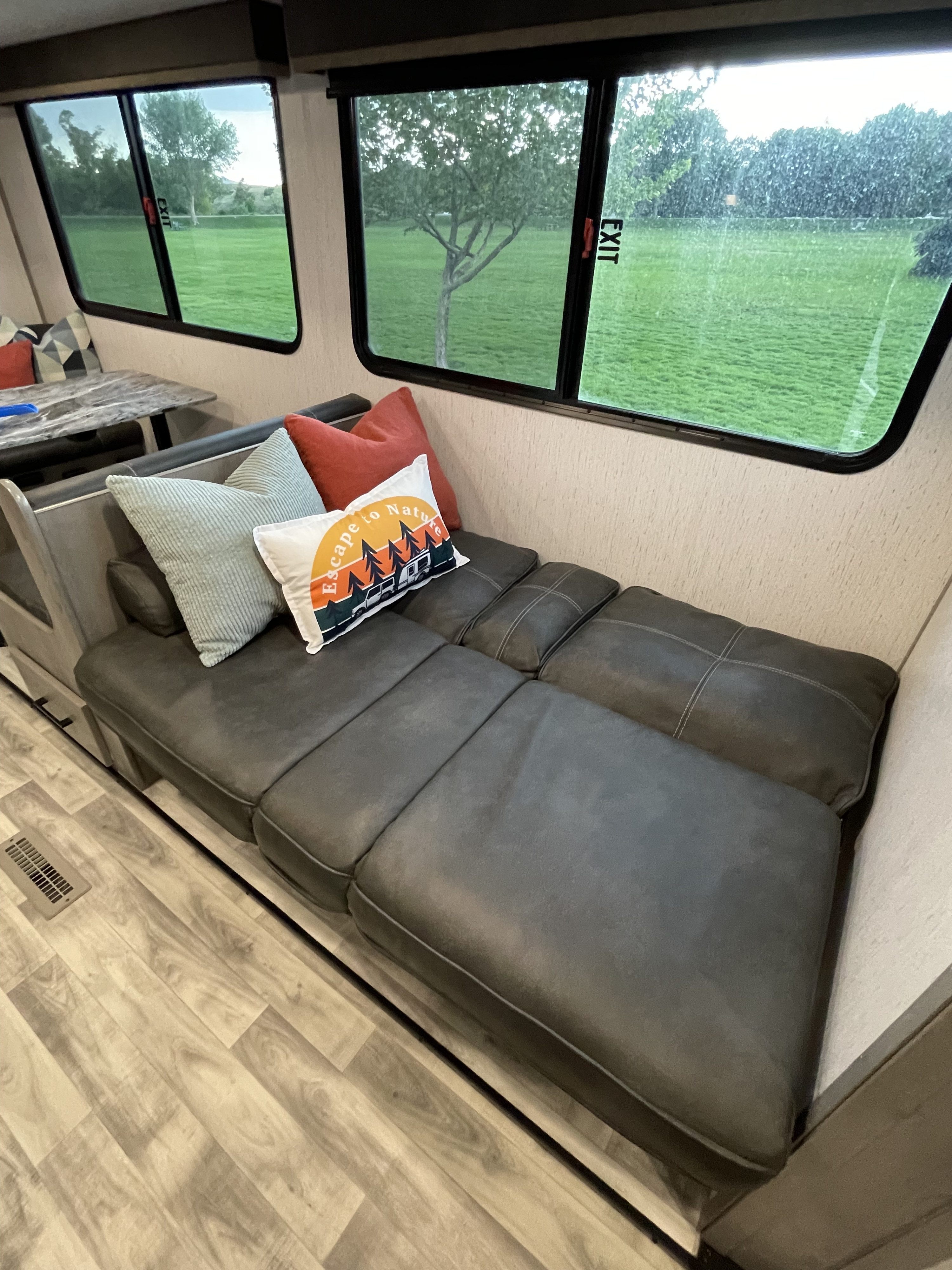 Cozy RV rental interior featuring a convertible sofa, dinette, and large windows with a scenic outdoor view.. Dutchmen Kodiak Ultra Lite 2021