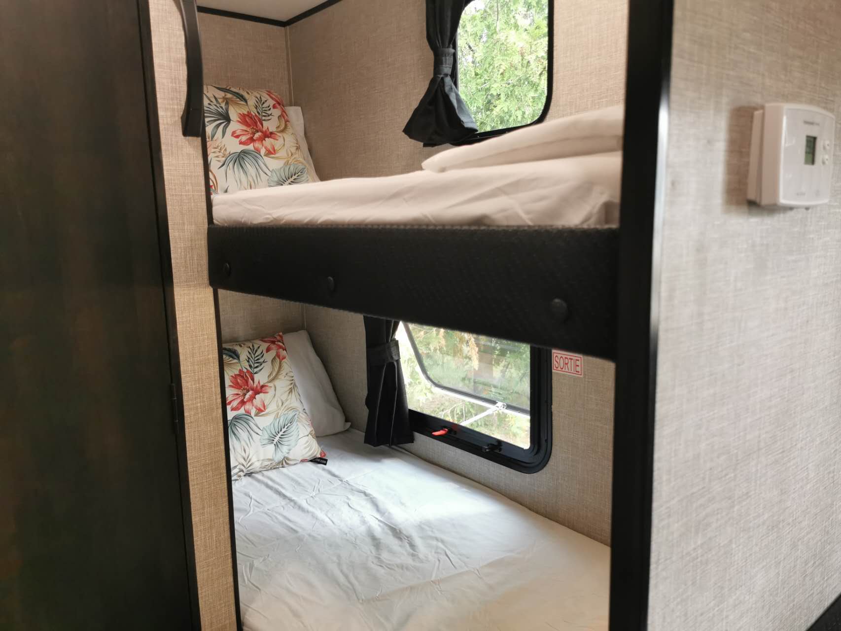 RV rental interior: two cozy bunk beds with windows, floral pillows, and soft bedding. Great for sleeping!. Jayco Jay Flight SLX 2022