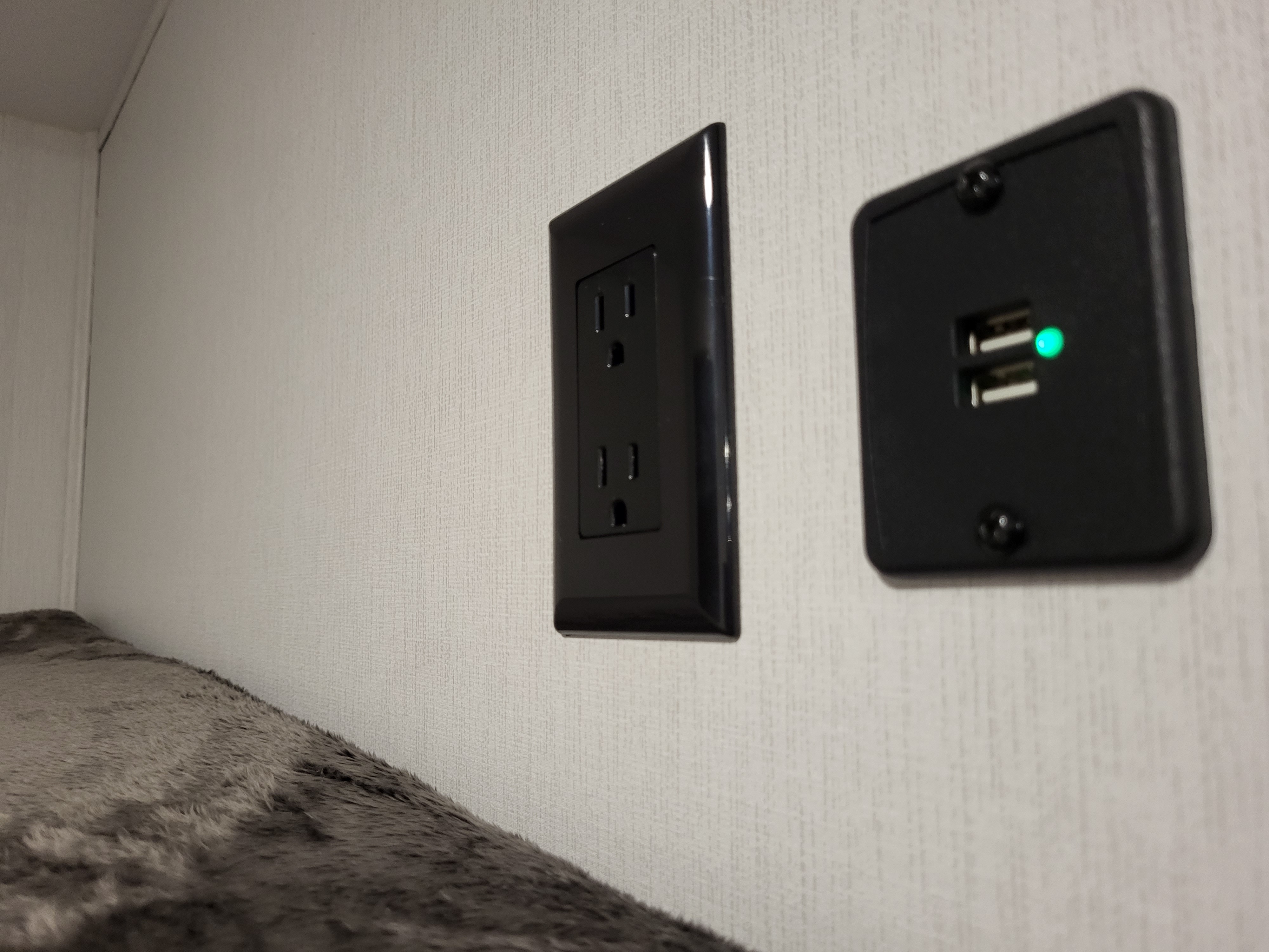 RV rental interior: A standard electrical outlet and a USB charging port with a green indicator light are mounted on a wall above a bunk.. Coachmen Freedom Express Ultra Lite 257BHS 2023