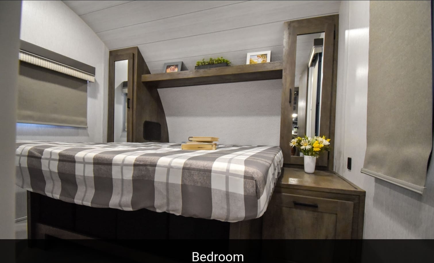 Cozy RV rental bedroom with plaid bedding, ample storage, and natural light. Perfect for your mobile adventures!. Forest River Wildwood X-Lite 2023