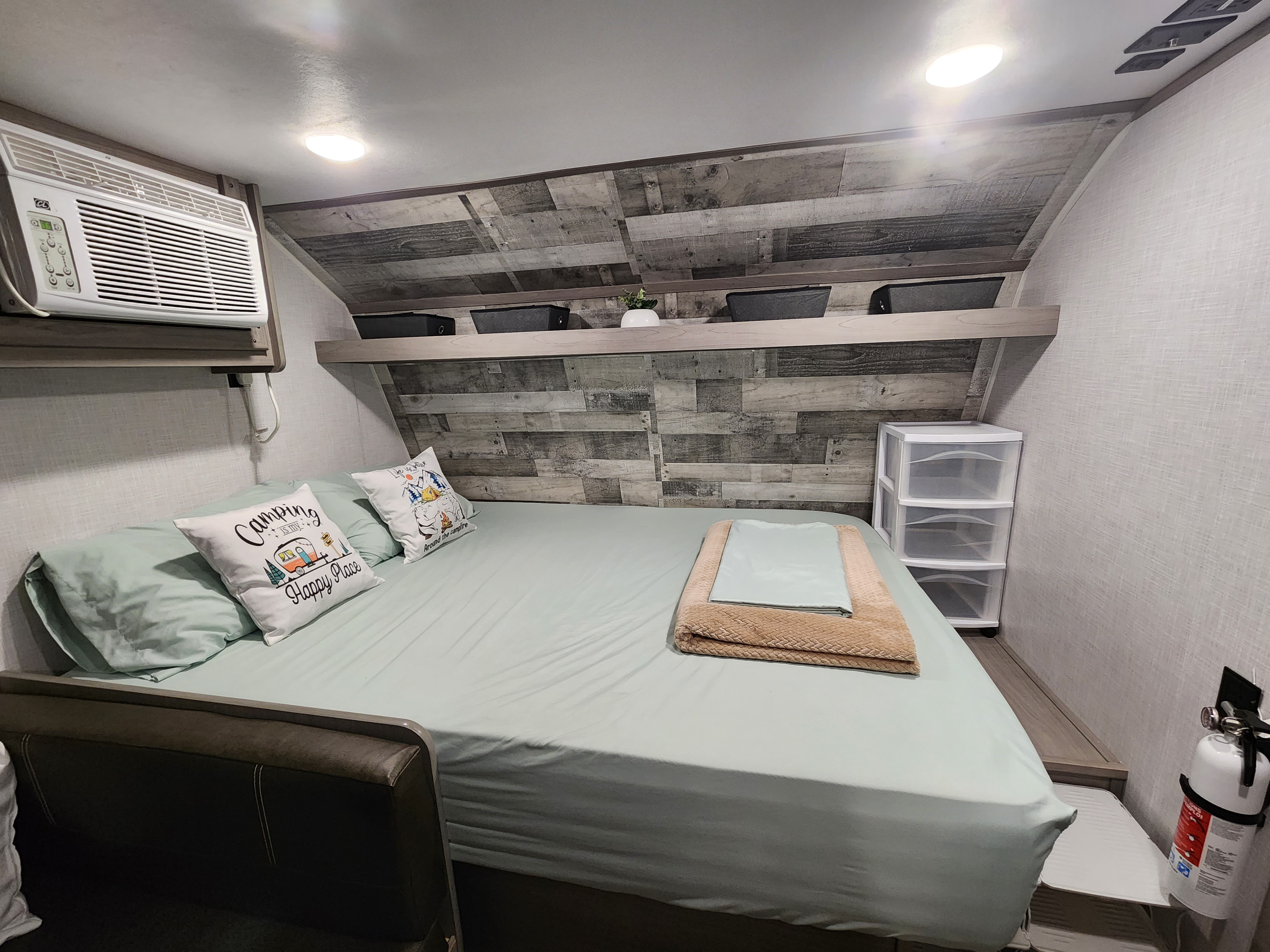 Relax in this RV rental bedroom: large bed, overhead AC, storage, and safety features like a fire extinguisher.. Dutchmen Coleman Lantern LT 2022