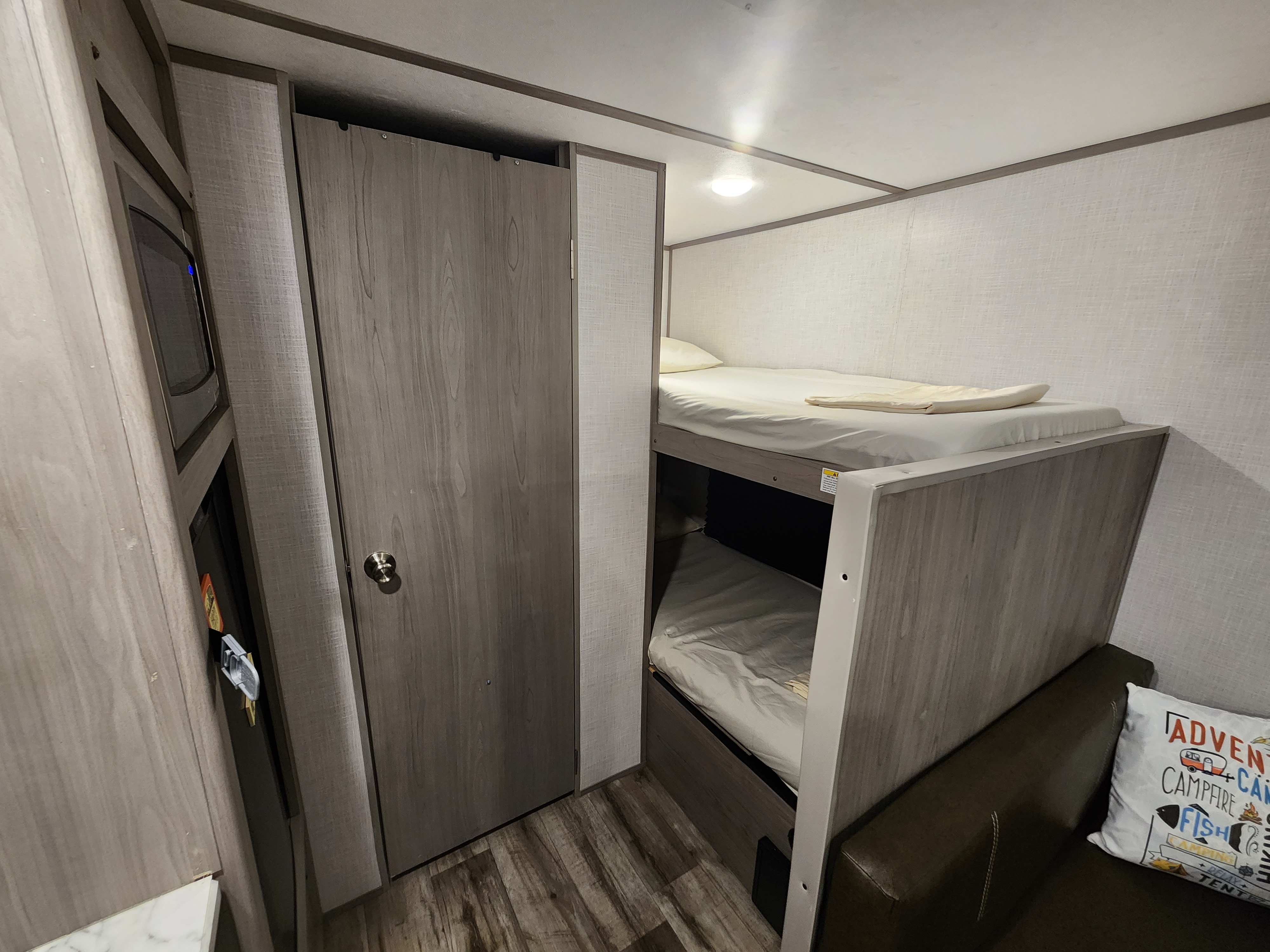 Cozy RV rental interior with bunk beds, a compact closet, and microwave, perfect for family travel.. Dutchmen Coleman Lantern LT 2022