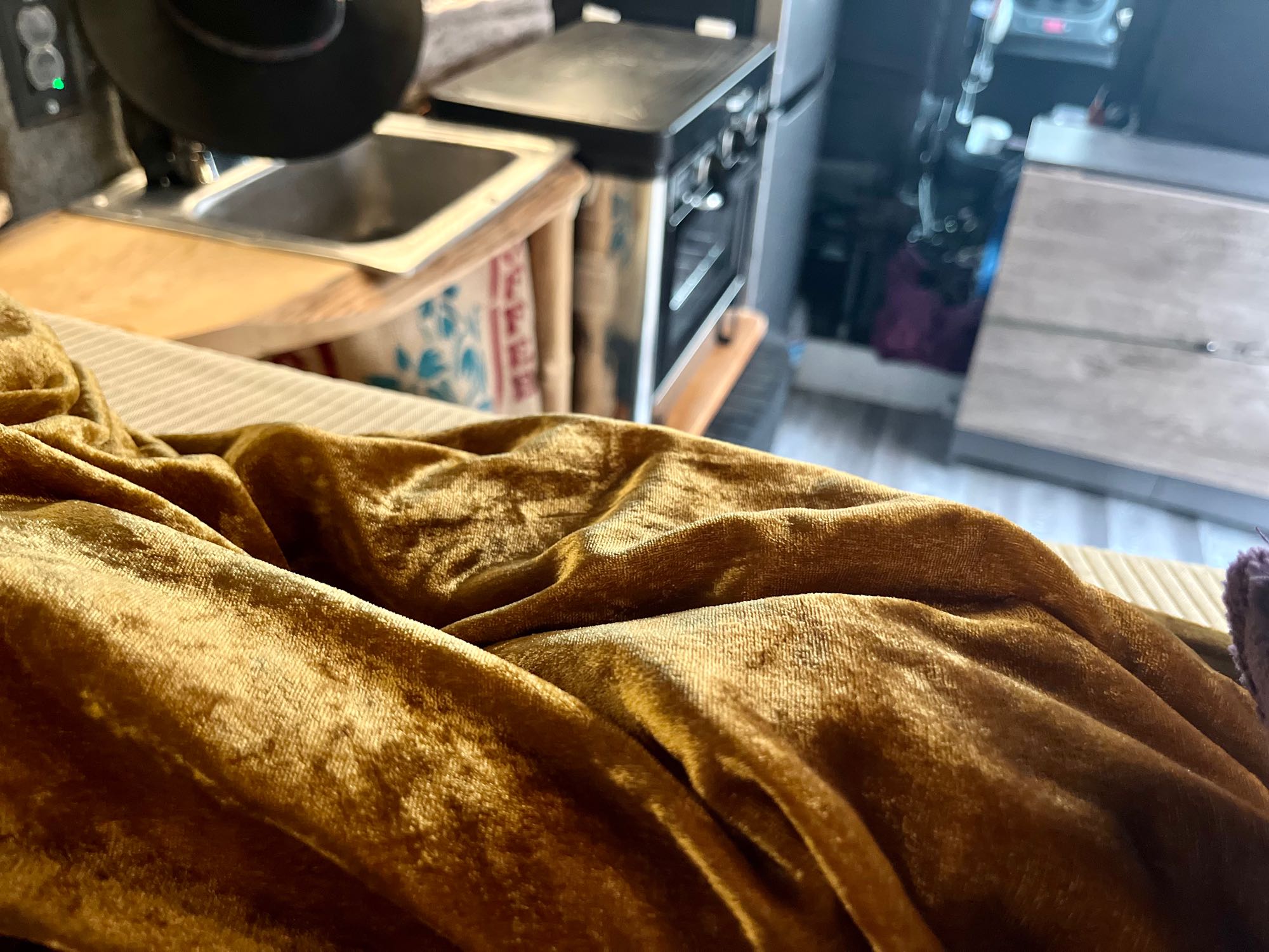 Cozy RV rental interior showing a compact kitchen with a sink, oven, and golden velvet fabric.. Dodge Other 2018