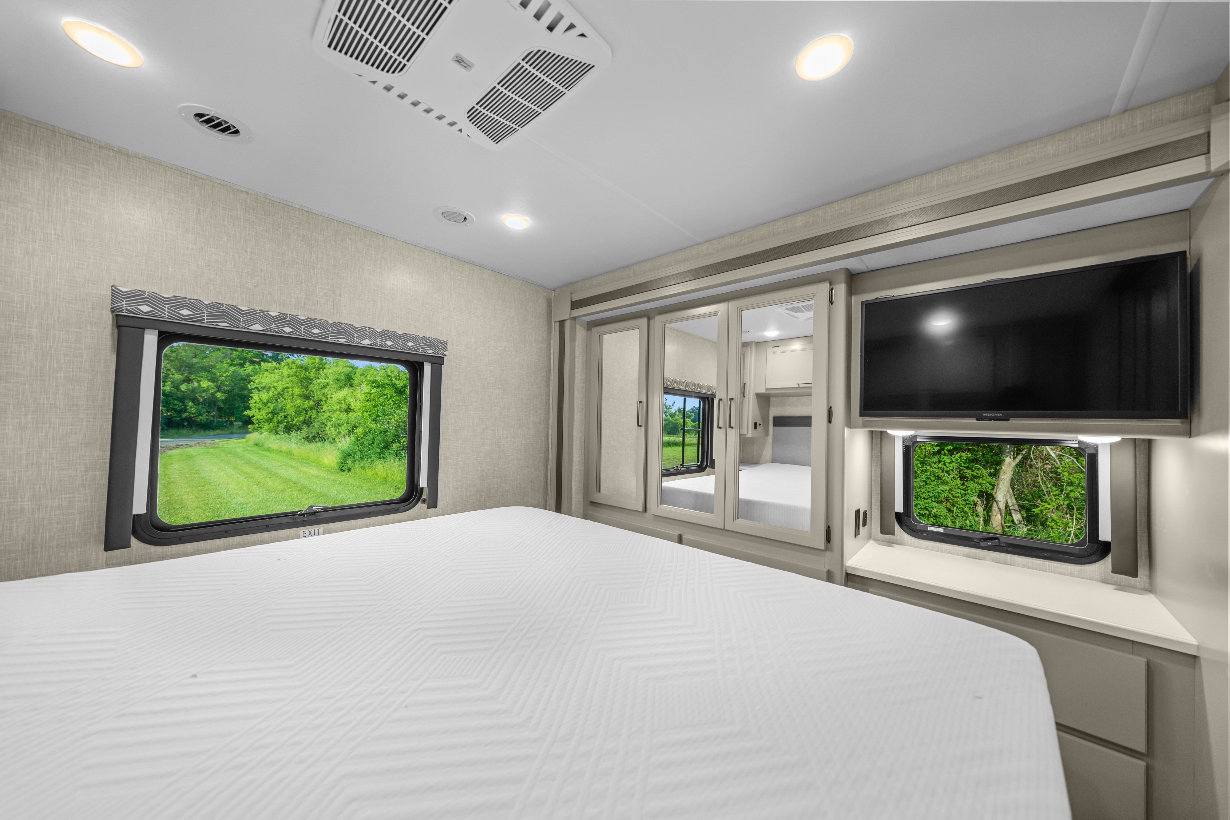 Spacious RV rental bedroom with a comfortable bed, TV, and scenic windows, offering a cozy retreat on wheels.. Thor Windsport 2023