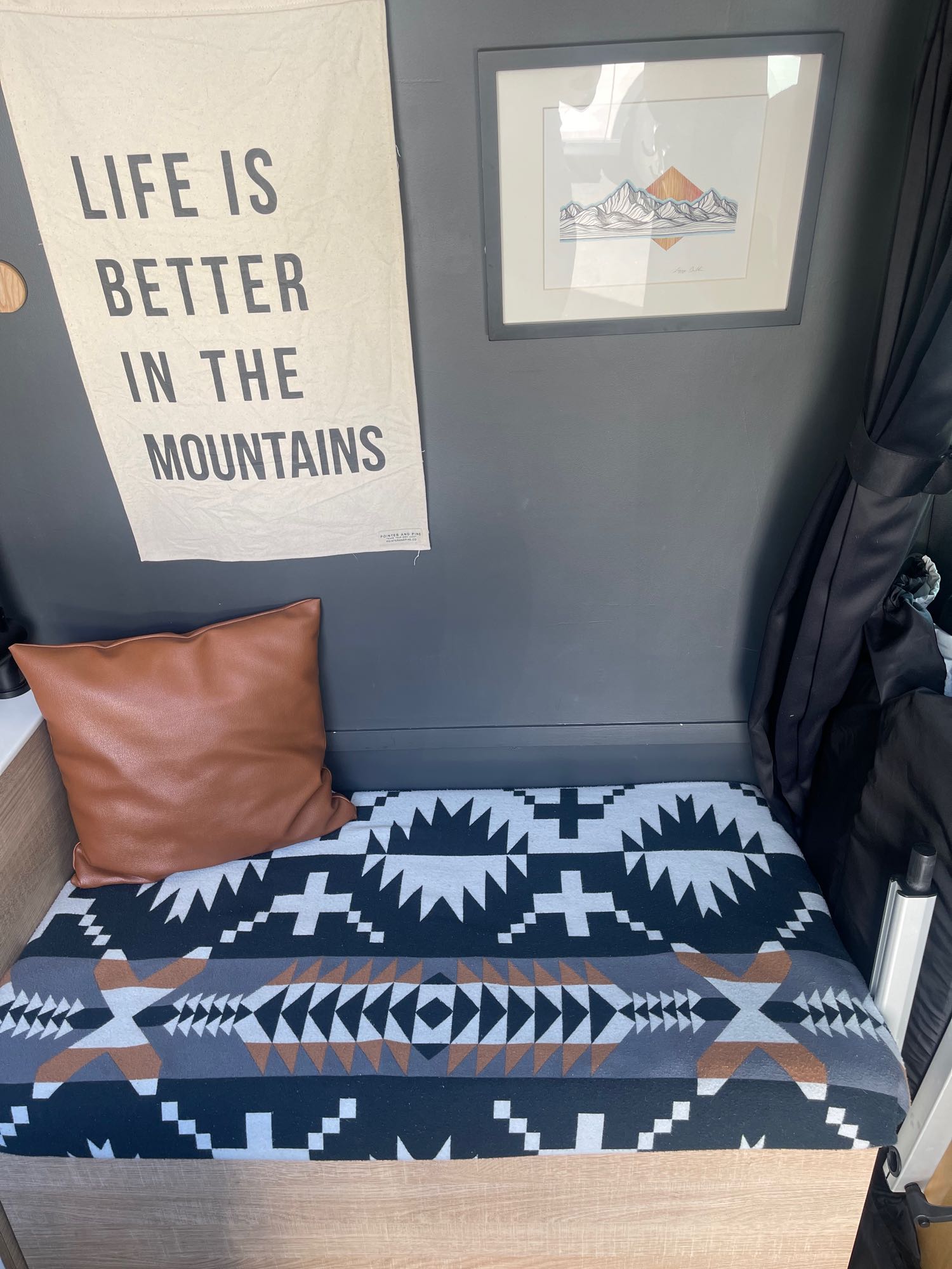 Cozy RV rental interior: "Life is Better in the Mountains" banner, framed art, comfy pillow & patterned blanket.. Mercedes Sprinter 2019