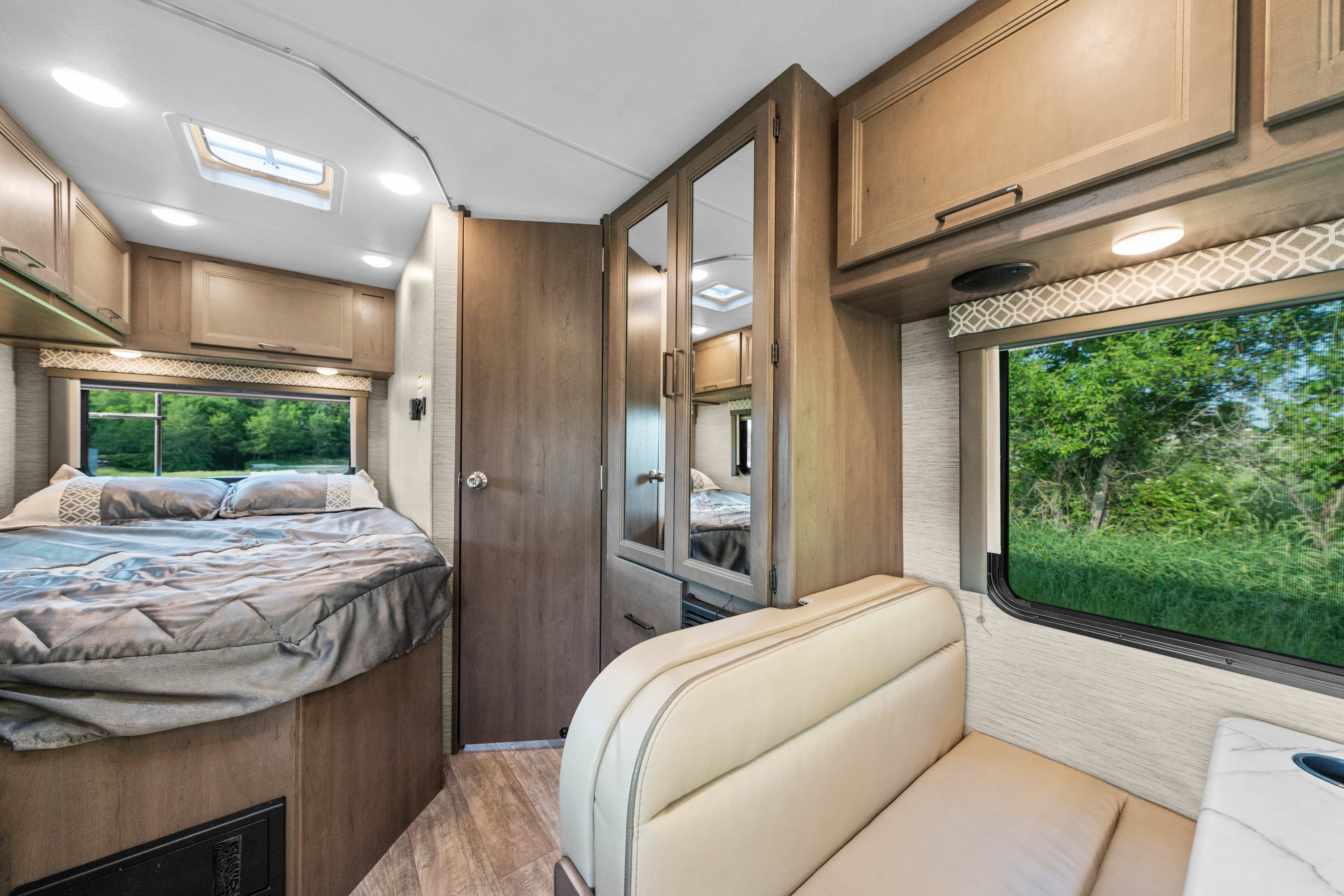 Spacious RV rental interior with a cozy bed, bright windows, comfortable dinette seating, and ample storage for travel.. Thor Coleman 2023