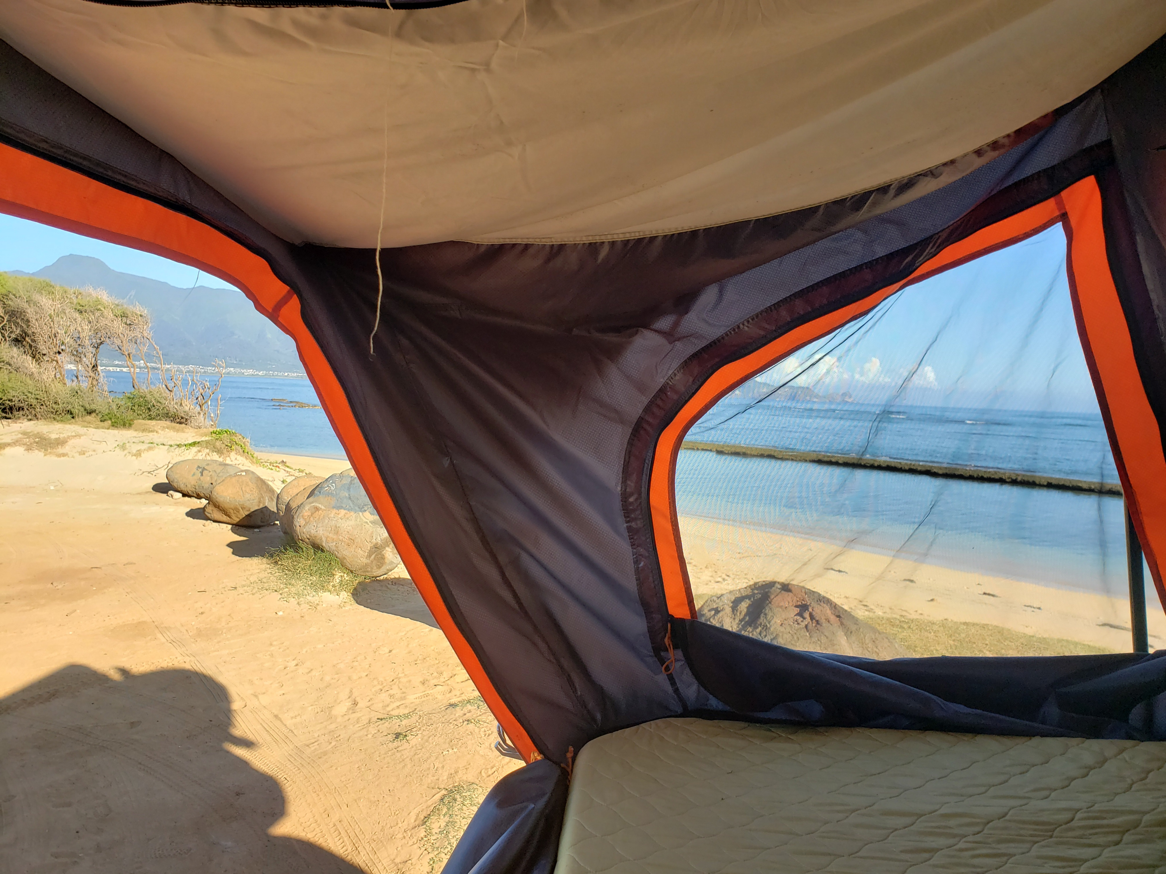 Serene beach and ocean view from inside an RV rental rooftop tent, with mountains in the distance. Ideal for coastal camping.. Other Other 2015