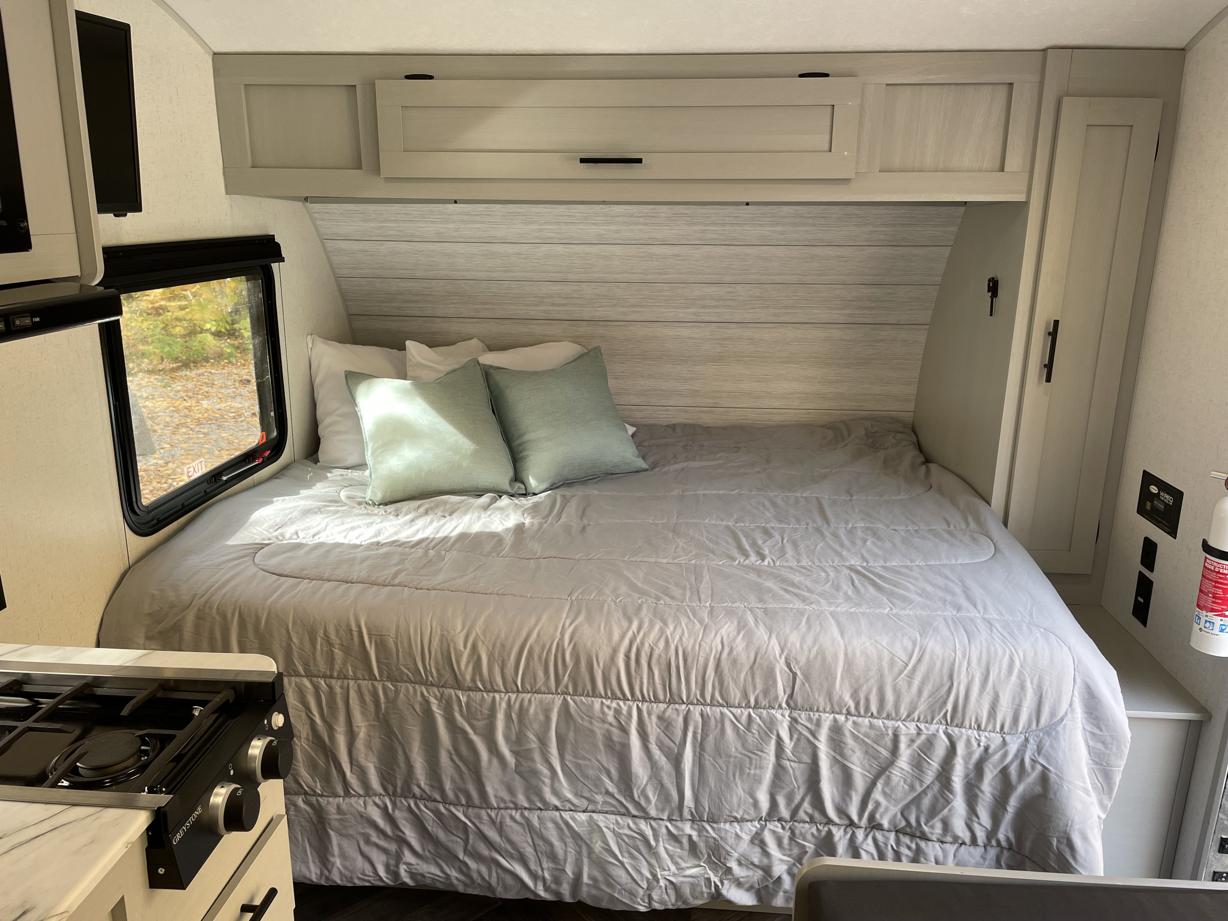 Inside an RV rental bedroom featuring a full-size bed, ample storage, and a scenic window view, perfect for cozy travels.. Forest River Salem FSX 179DBK 2022
