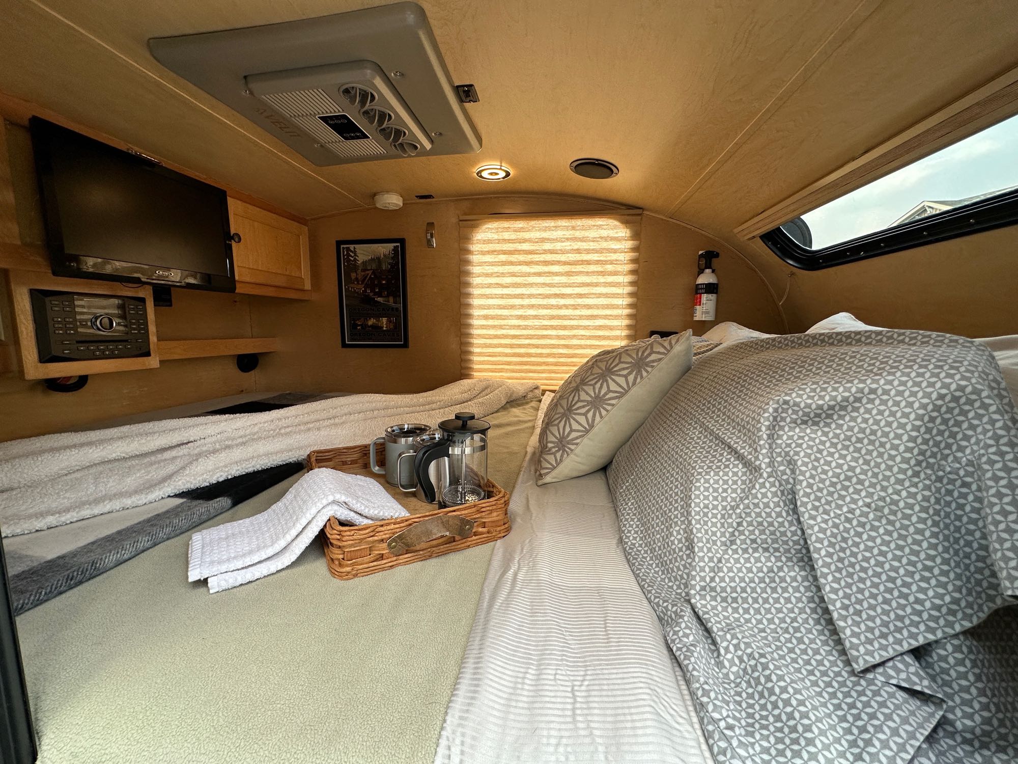Cozy RV rental interior with a comfortable bed, TV, and morning coffee setup on a tray. Ideal for your next trip.. Little Guy Little Guy Trailer 2013