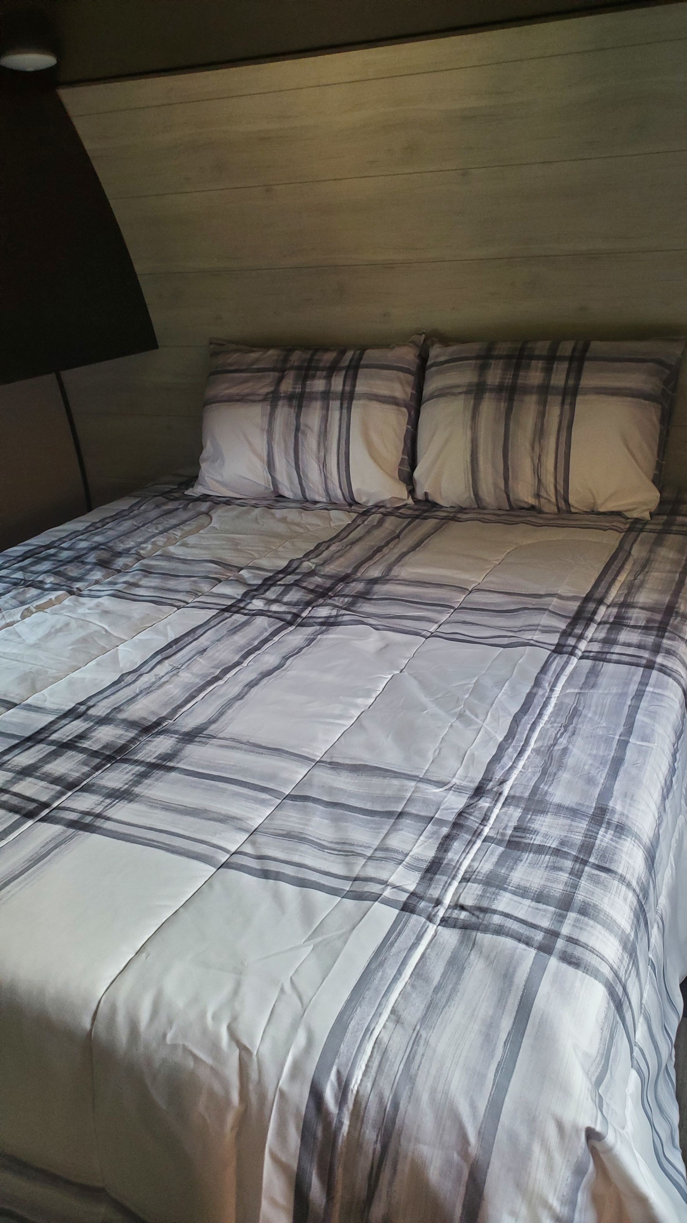 Cozy RV rental bed with stylish gray and white plaid bedding and wood paneling, offering a comfortable sleeping area.. Jayco Jay Flight 264BH 2023