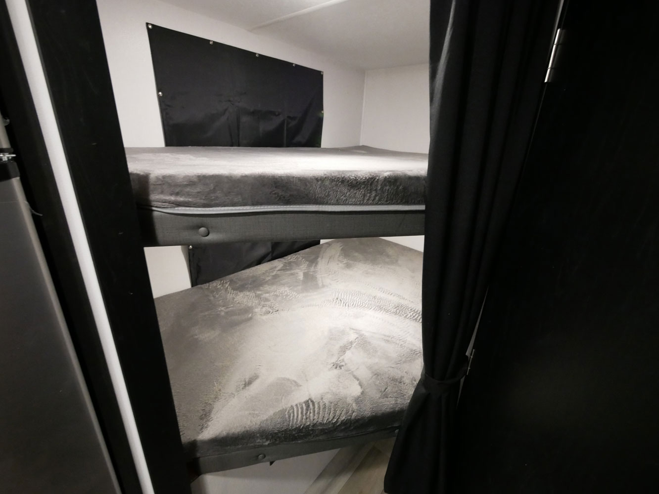 Inside an **RV rental**: two comfy bunk beds with grey bedding and black privacy curtains.. Coachmen 257BHS 2022