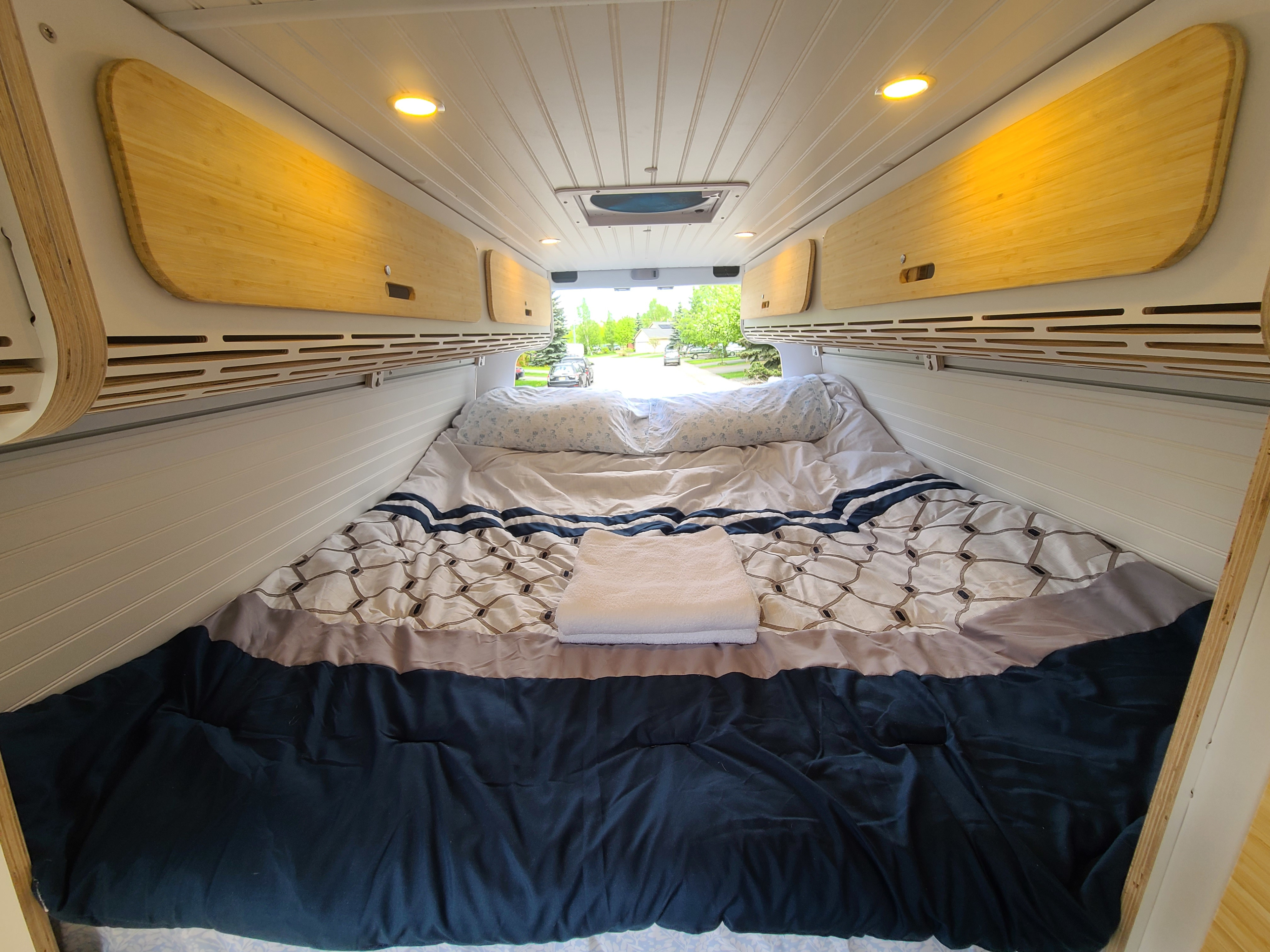 RV rental bedroom: cozy bed, warm bamboo overhead storage, and bright ceiling lights for comfort.. Mercedes Sprinter 2013