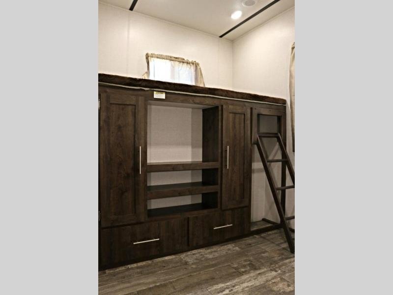 RV rental interior featuring a bunk bed, ladder, and a dark wood cabinet unit with storage shelves and drawers for a cozy sleeping area.. Crossroads RV Volante HP 2018