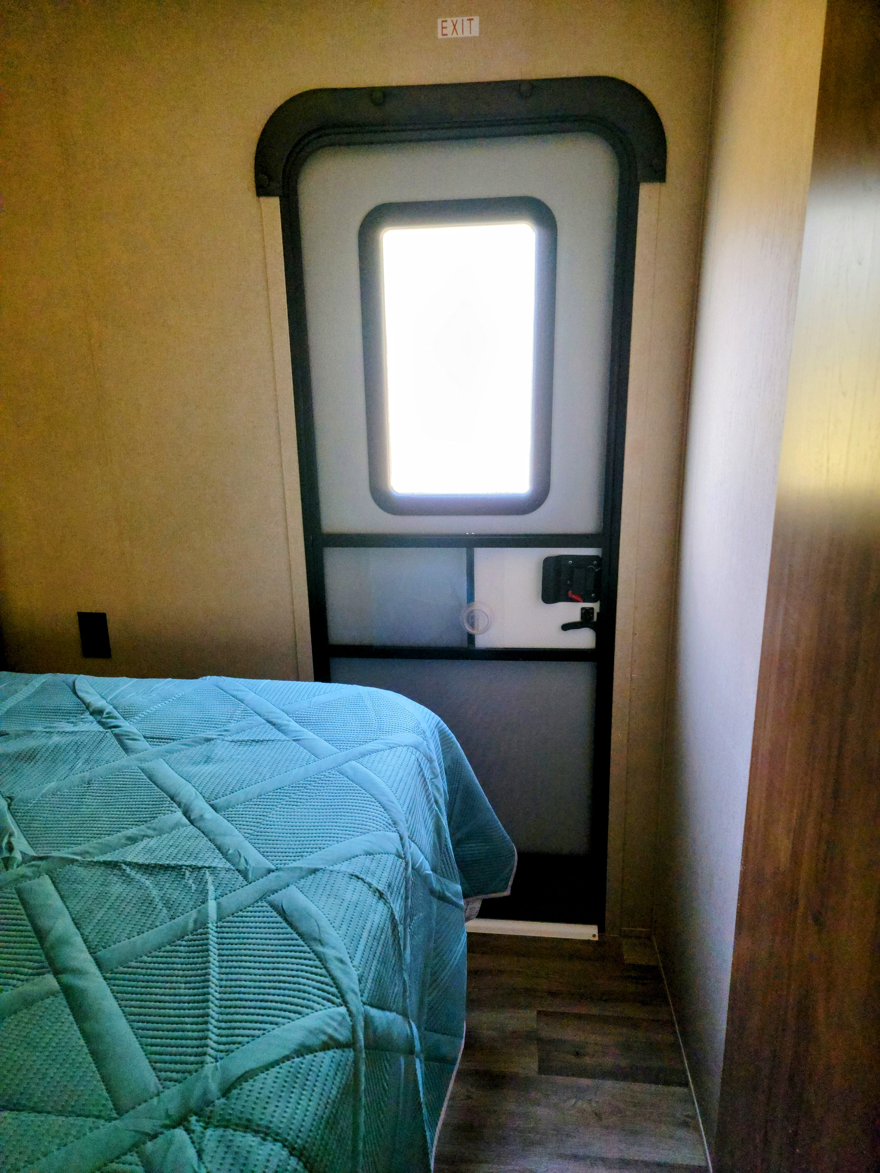 RV rental: Interior shows a main exit door with a bright window, next to a bed with a teal comforter.. Aspen Trail Aspen Trail Trailer 2018