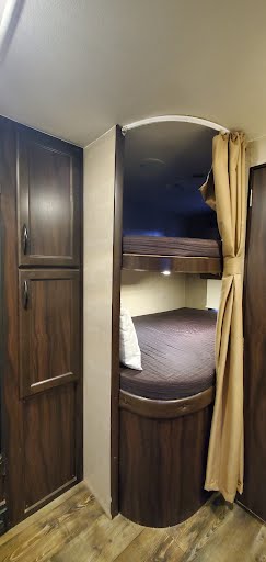 RV rental interior: cozy compact bunk beds with dark bedding, built-in cabinets, and a privacy curtain, ideal for travel.. Pacific Coachworks Panther Xtralite 2019