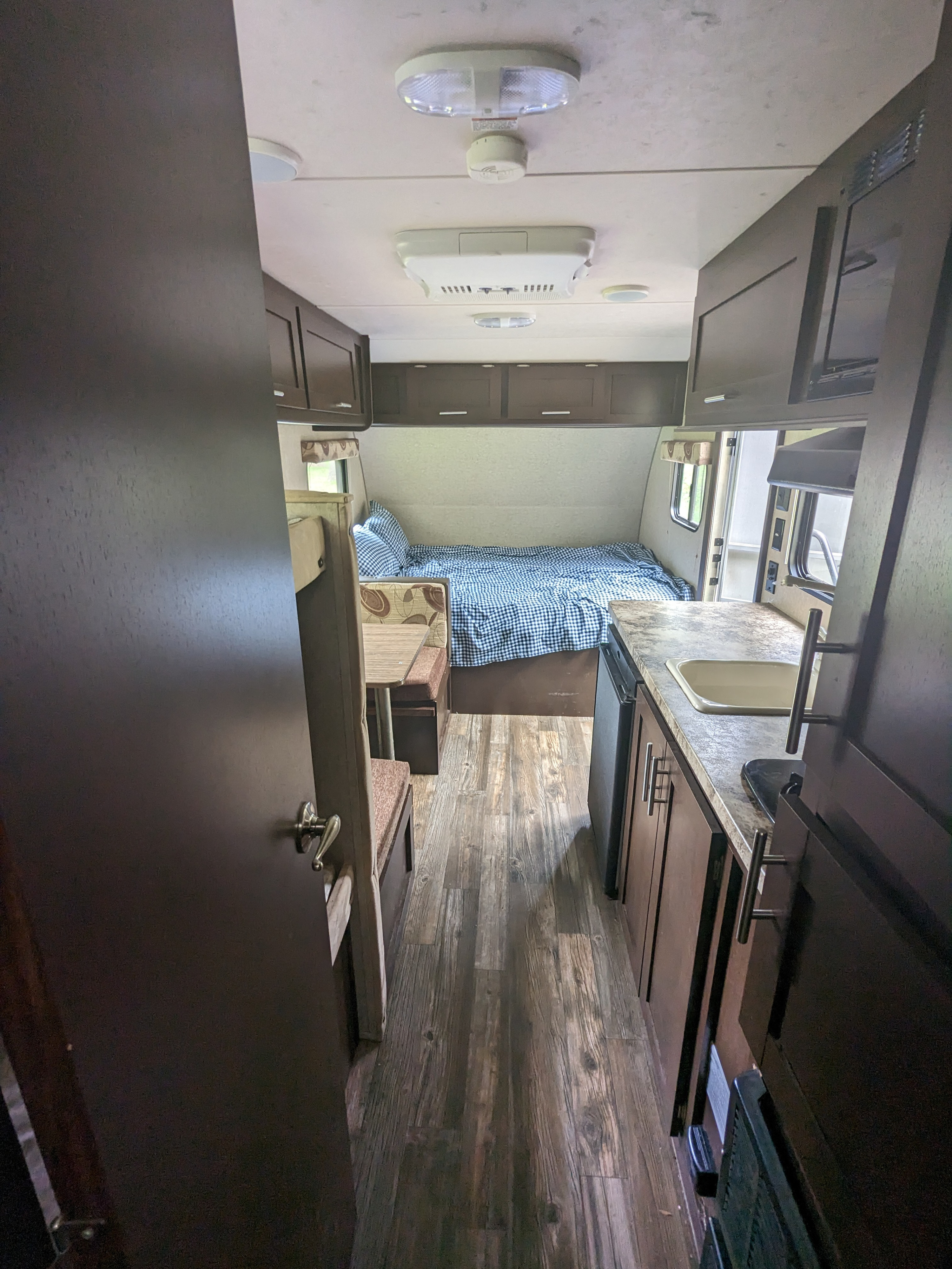 Inside a bright **rv rental**, showing a comfortable bed, dining booth, and kitchen area. Perfect for travel adventures.. Forest River Cherokee Wolf Pup 2016