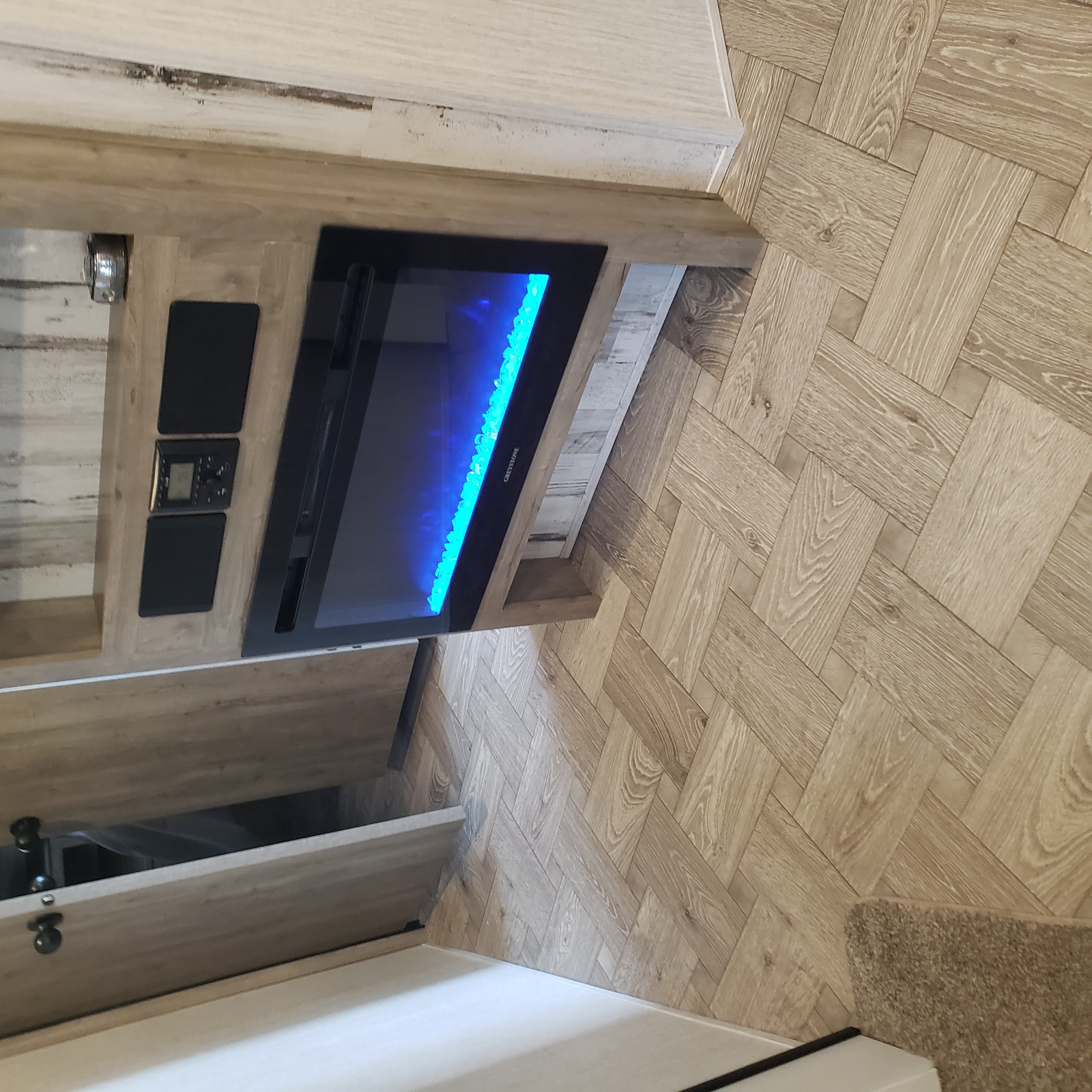 RV rental interior with a modern electric fireplace displaying blue flames, herringbone flooring, and control panels.. Forest River Palomino Puma 2021