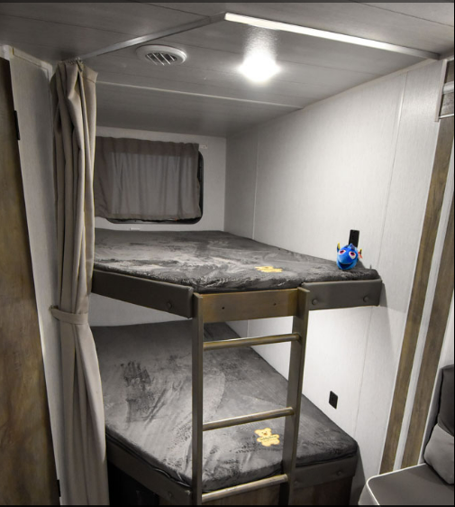 Cozy RV rental with grey bunk beds, featuring a Dory toy. Perfect for family camping adventures.. Forest River Wildwood X-Lite 2021