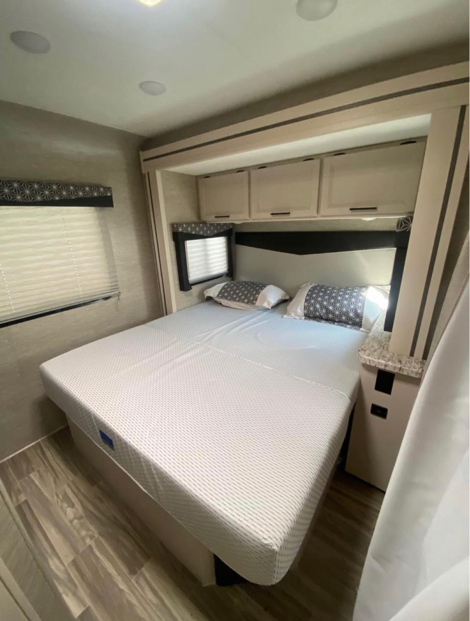 This clean RV rental bedroom features a comfortable bed, overhead storage, and blinds for privacy.. Thor Freedom Elite 2022